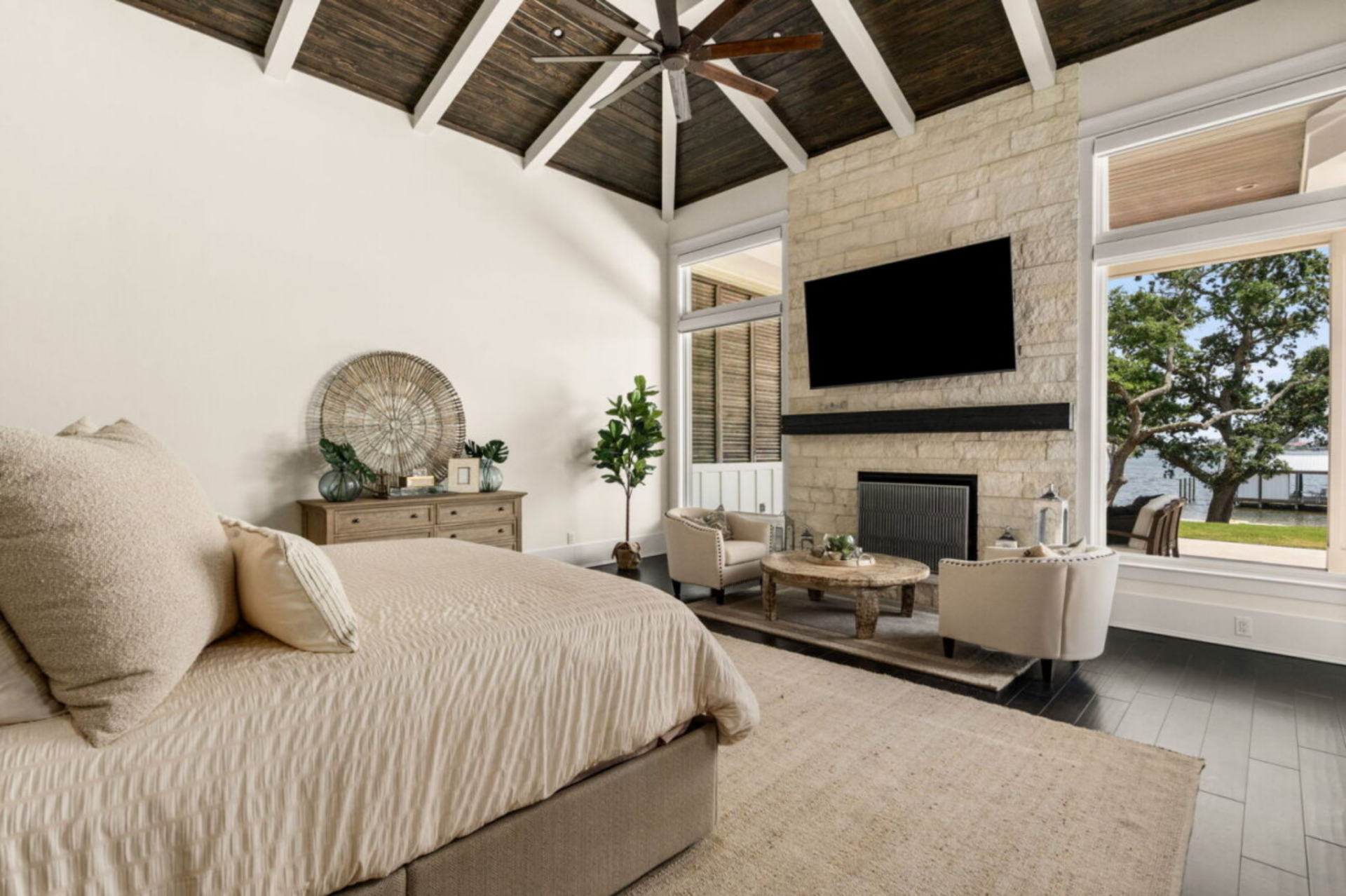 The primary suite continues the home’s light and airy design with soaring vaulted ceilings finished in dark wood planks and exposed beams. 