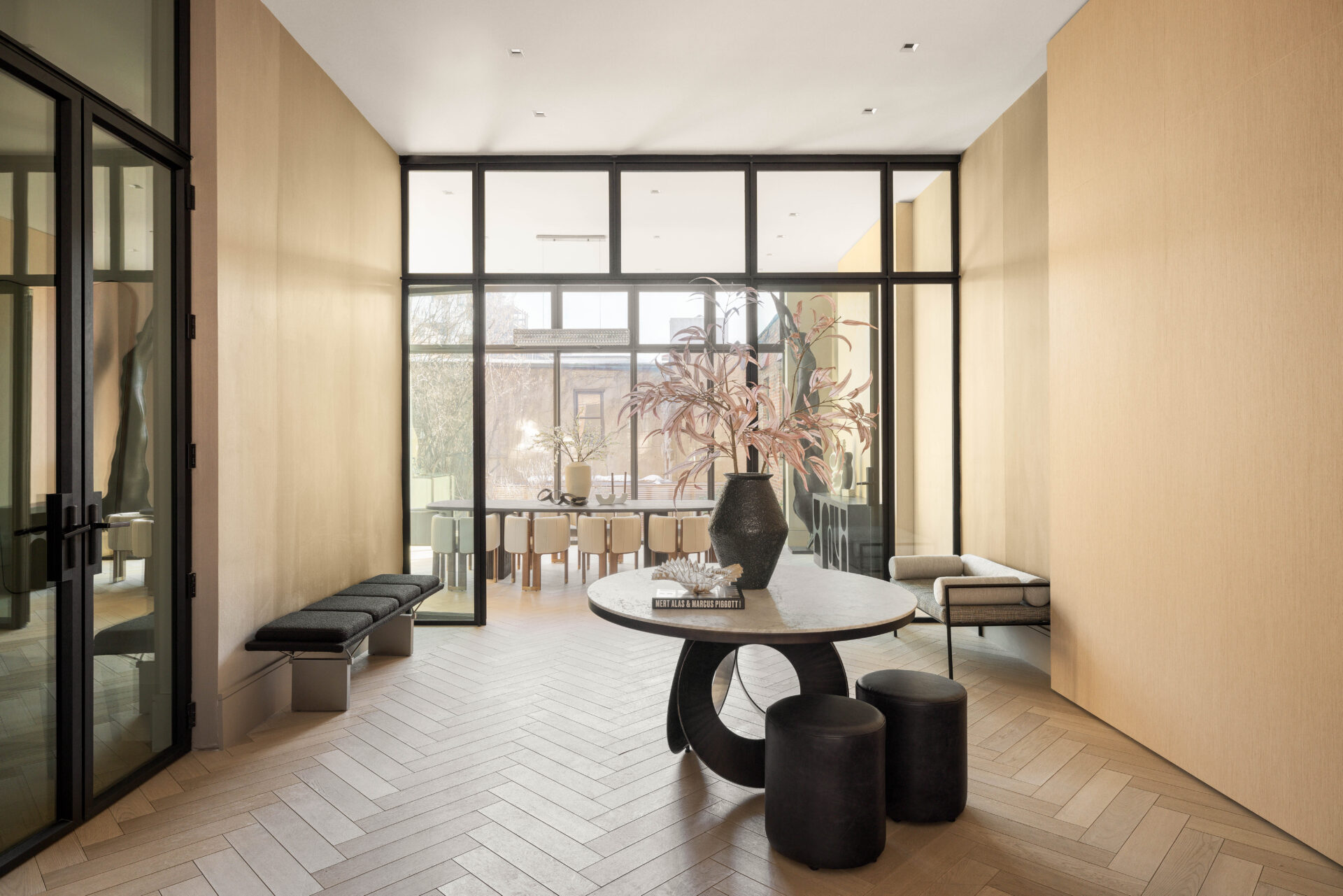 The parlor level begins with a central foyer, grounded by herringbone wood flooring running throughout and clean-lined walls framing the space.