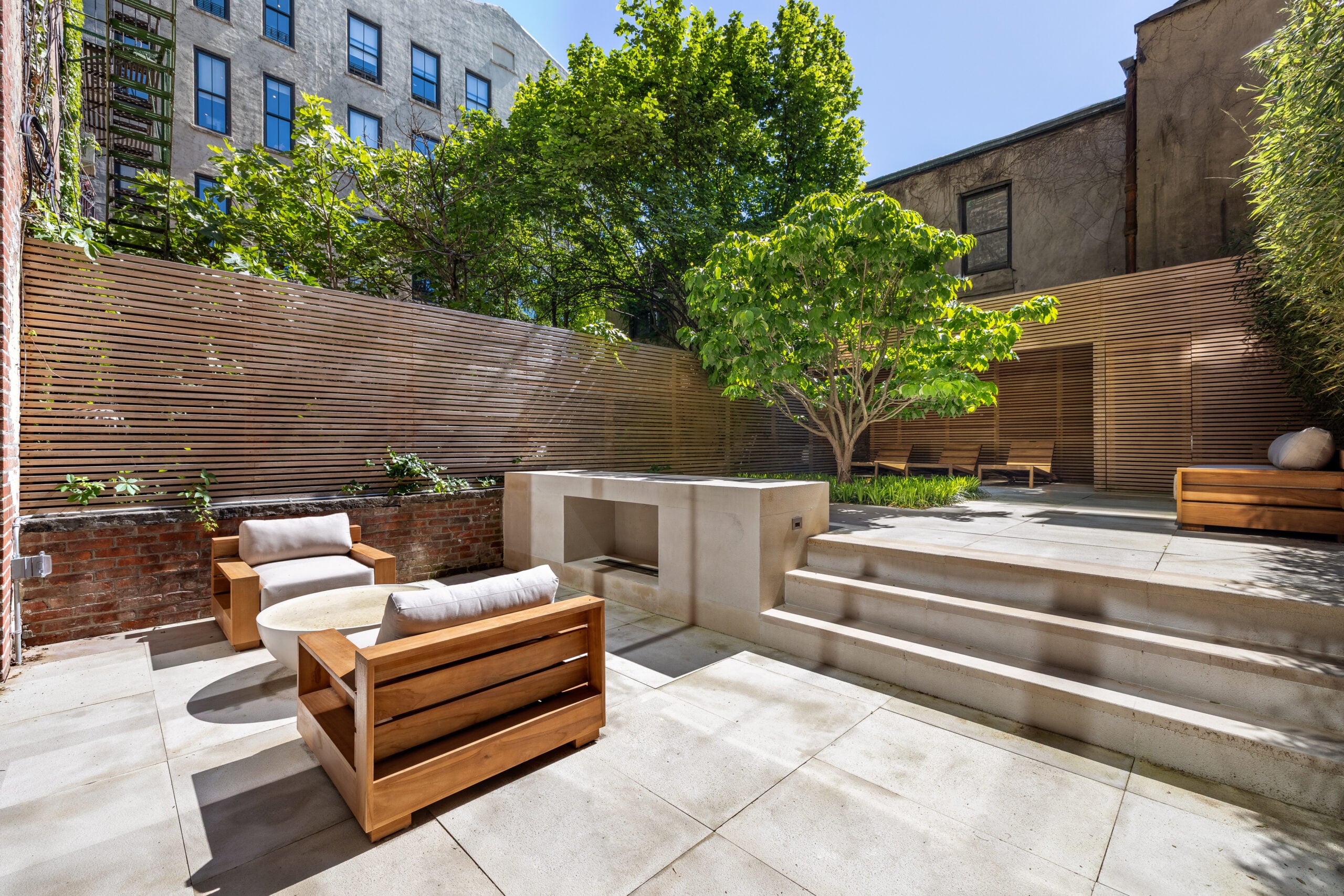 Extending directly off the garden level, a paved terrace sits just outside with a fireside lounge and shaded loungers.