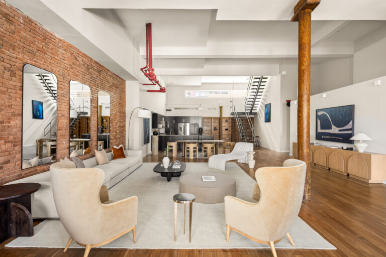 Arriving by private elevator, the loft opens directly into a wide great room where seventeen-foot ceilings lift above a full wall of oversized windows, drawing in natural light.