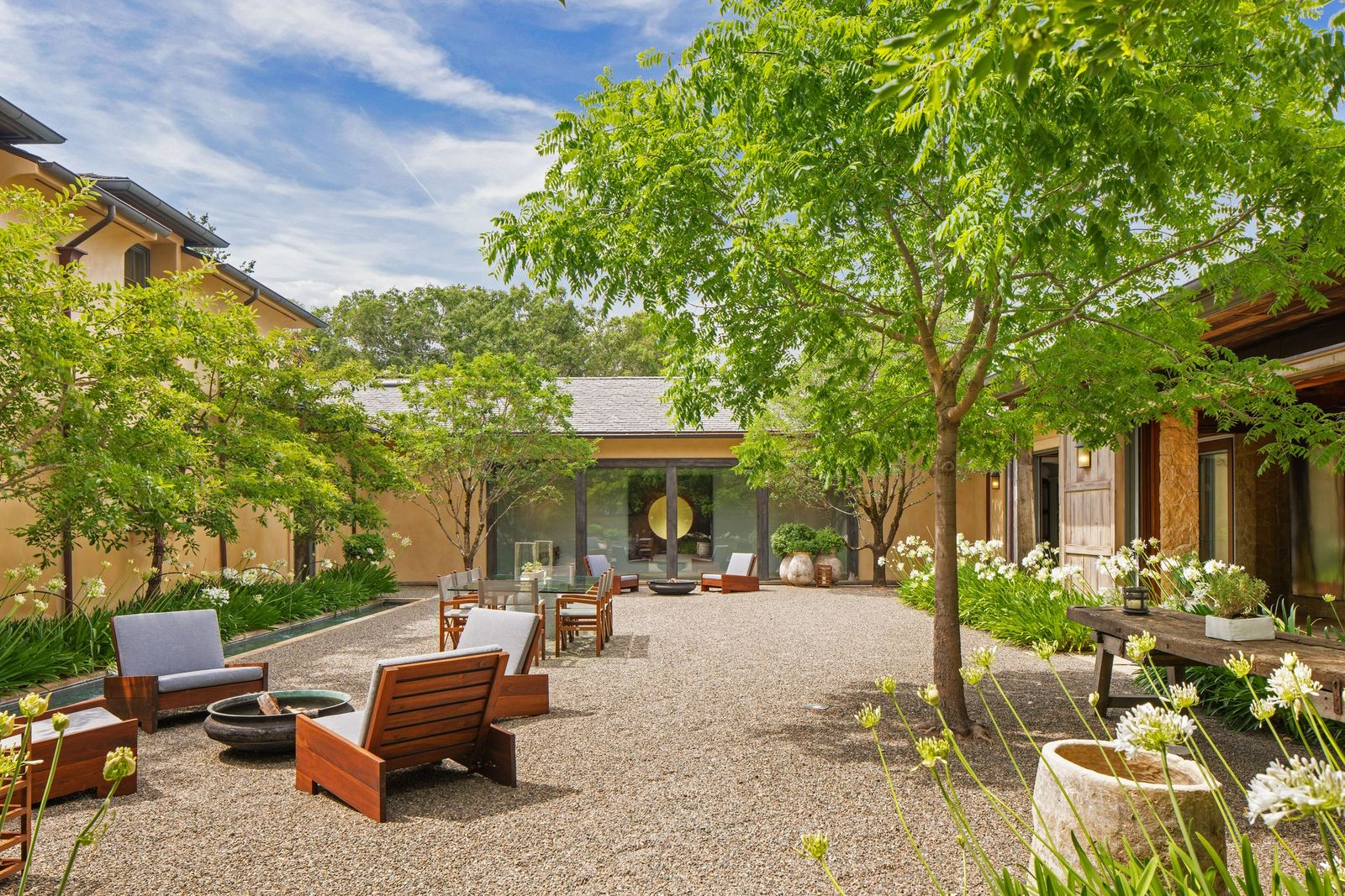From there, the house wraps around the central courtyard, with stone walls, timber detailing, and wide openings that keep the main structure visually tied to the rest of the estate.
