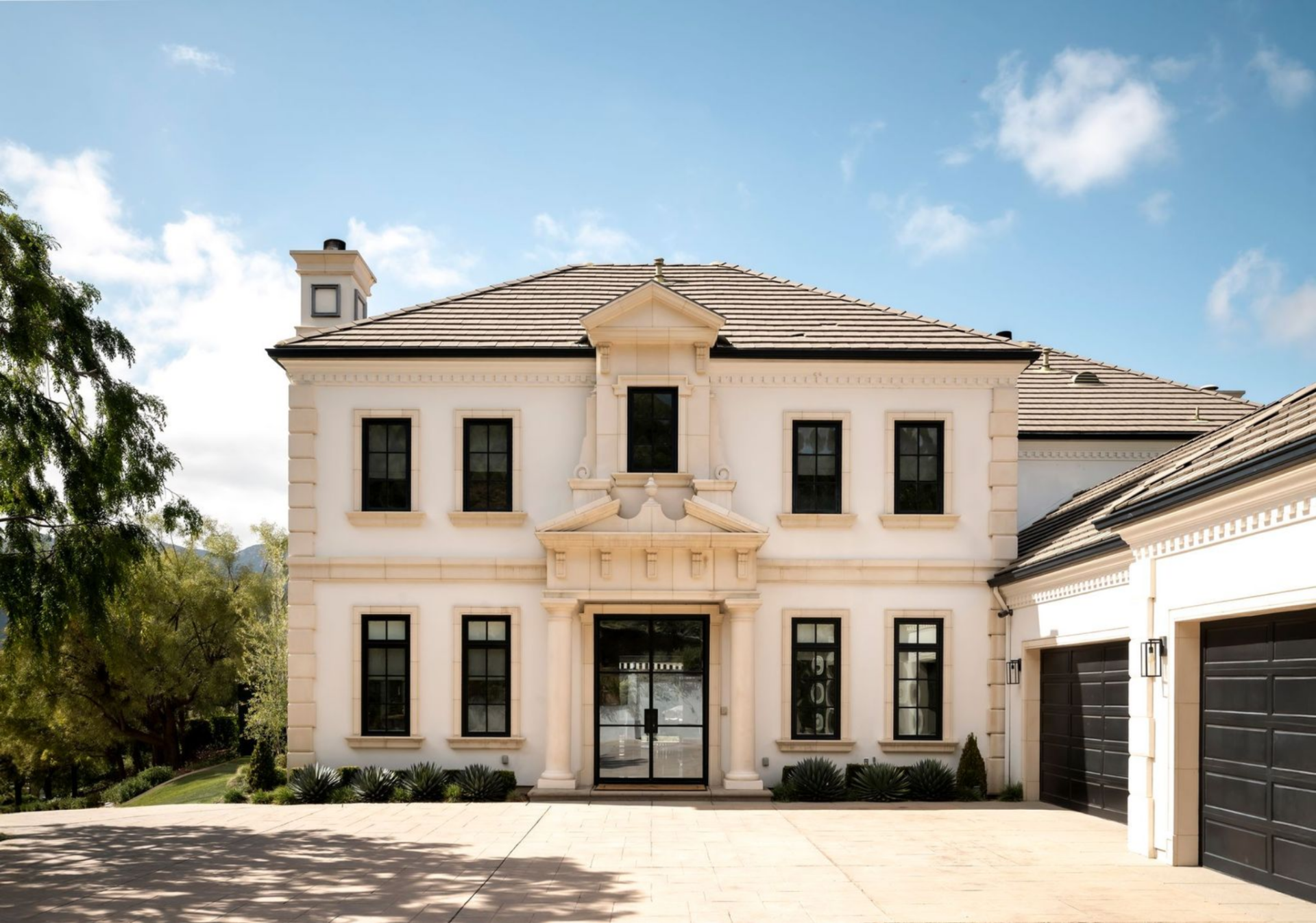 Classical trim around the doorway and upper pediment gives the front door a more traditional look, while the open paved court sets it up for a clean, estate-style arrival.