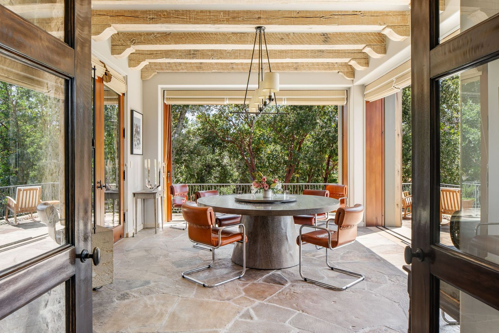 On the other side of the kitchen, the casual dining room is arranged with a round pedestal table set at the center surrounded by leather dining chairs with chrome frames.