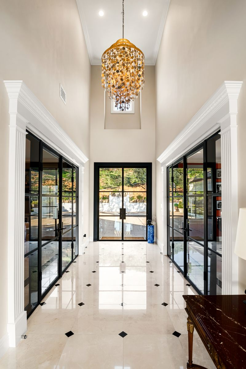 Stepping inside, the front door opens directly into a two-story entry that runs straight through the center of the home, drawing in natural light from the glass doors. 