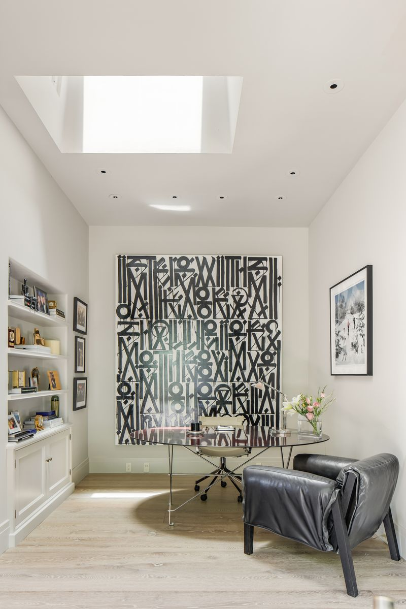 On one side of the bedroom, the office is set into a narrower, taller room with a skylight overhead that brings light straight down onto the desk area. 