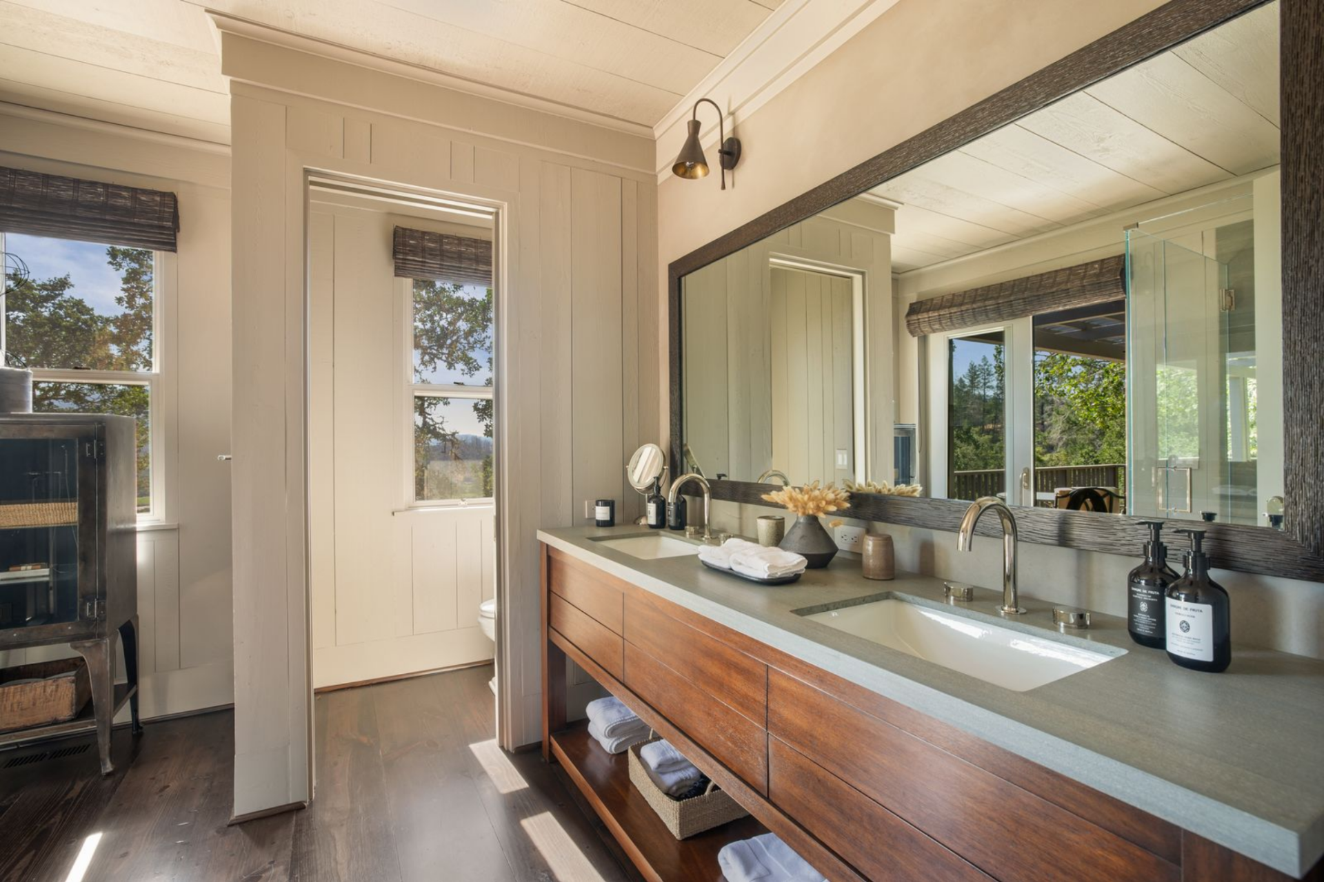 The bathroom is laid out with a double vanity beneath a large framed mirror and integrated lighting above. 