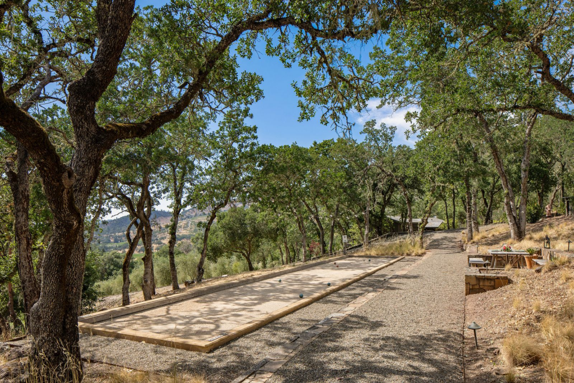 Set along a gravel pathway beneath a canopy of trees, the bocce court is integrated into the natural topography.