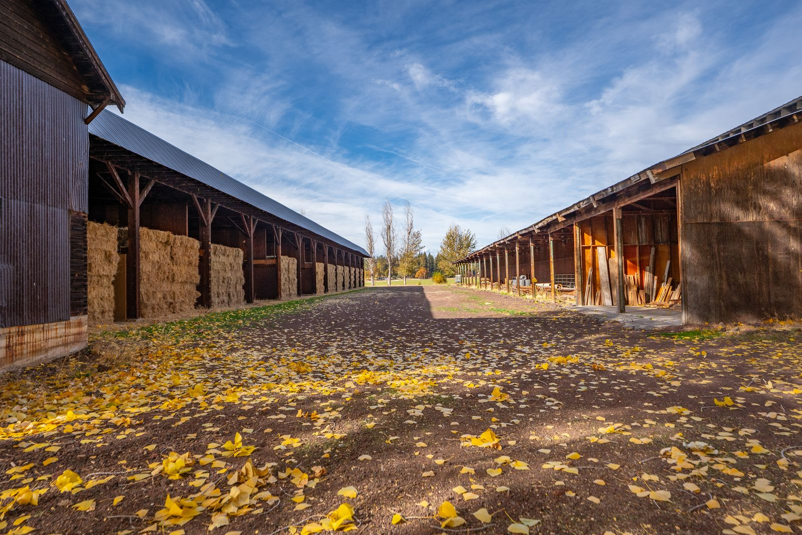 Two lines of barns stretching vertically filled with hay and farming supplies.