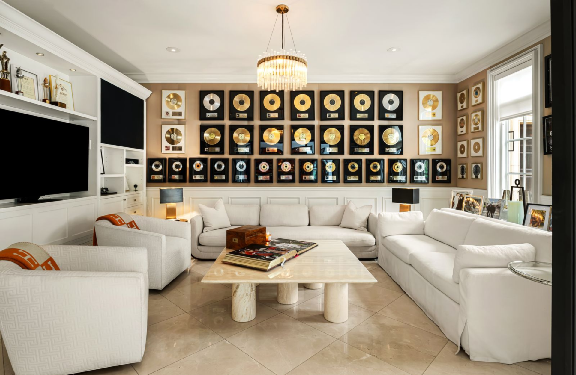 Just off the entry, the den opens behind black-framed glass doors and is anchored by a full wall of framed gold records. 