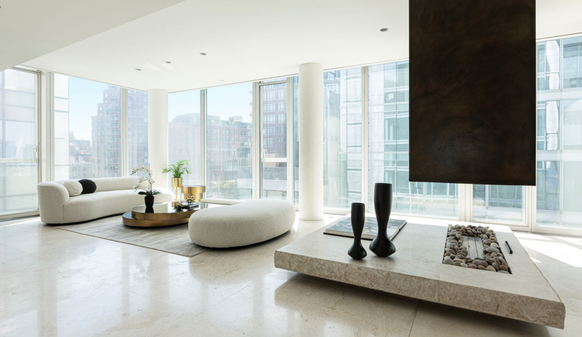 That lounge is set around a low ethanol fireplace with a thick stone surround, creating a second seating zone with a curved sofa, round ottoman, and low circular table.