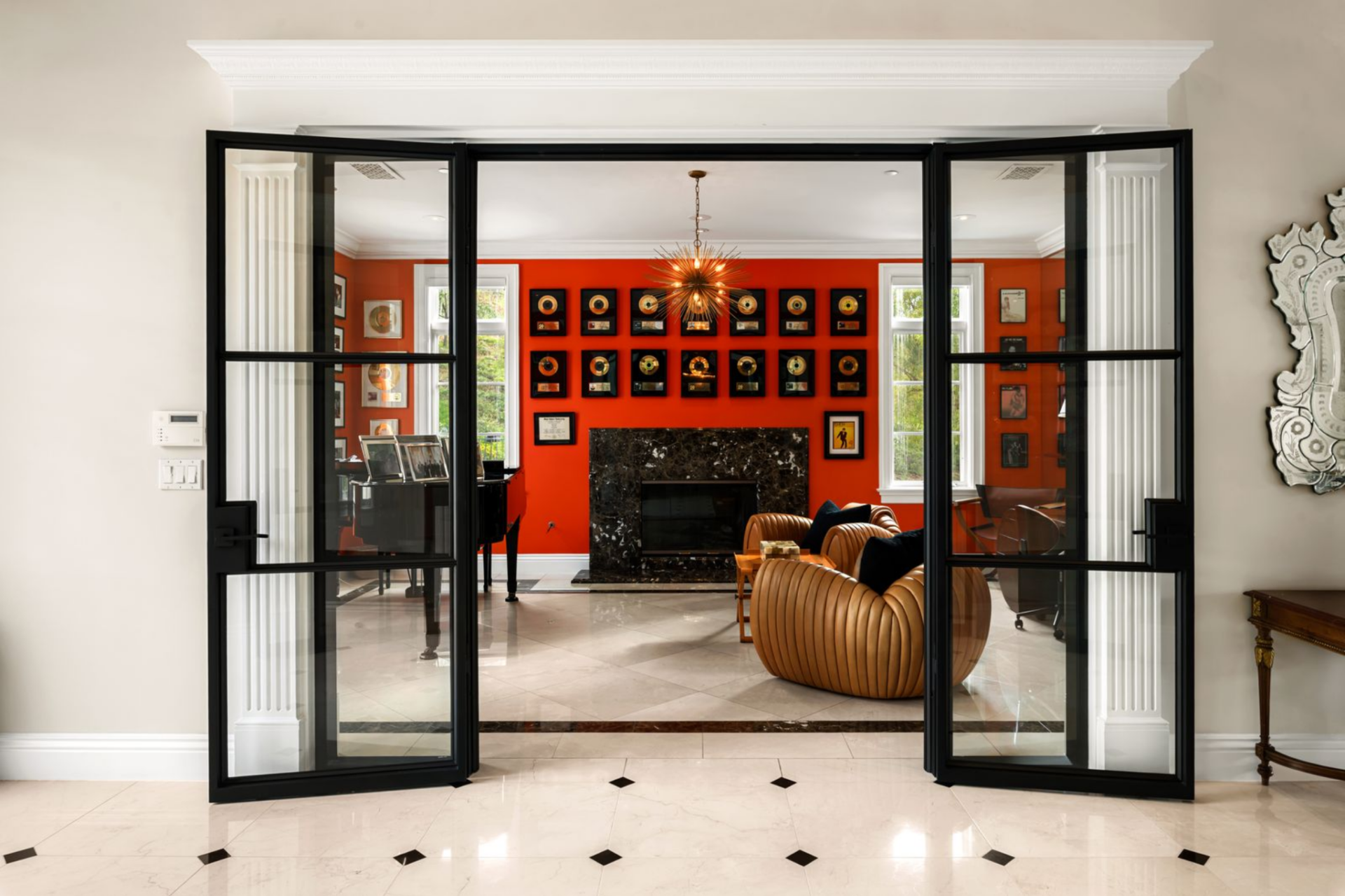 Across the hall, the piano lounge is organized around a central fireplace and a grand piano set to one side, with additional gold records mounted above the mantel. 