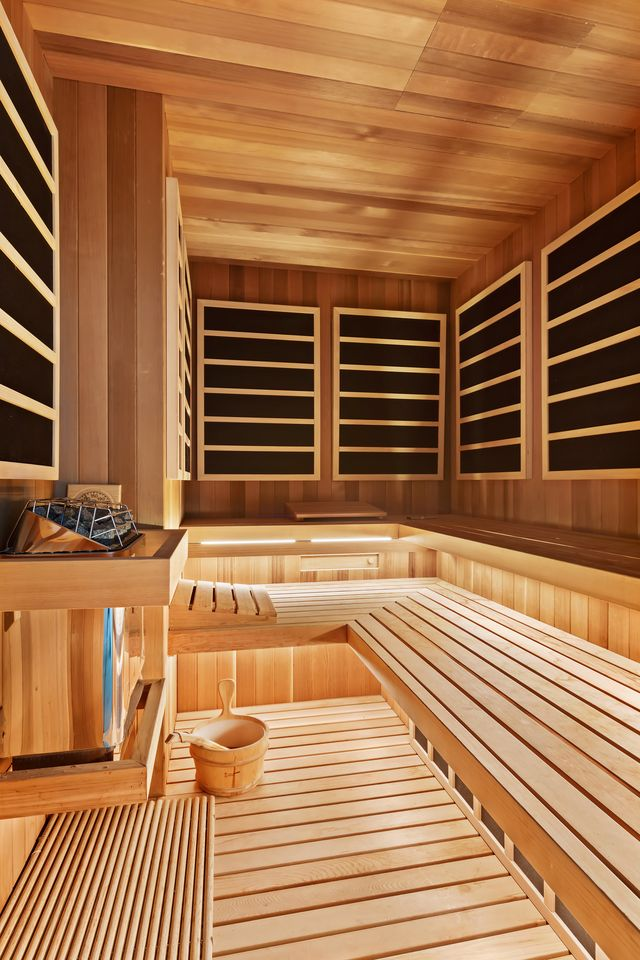 Around the corner, a wood-lined sauna adds to the spa atmosphere with tiered bench seating and integrated lighting, creating a dedicated wellness zone within the suite.