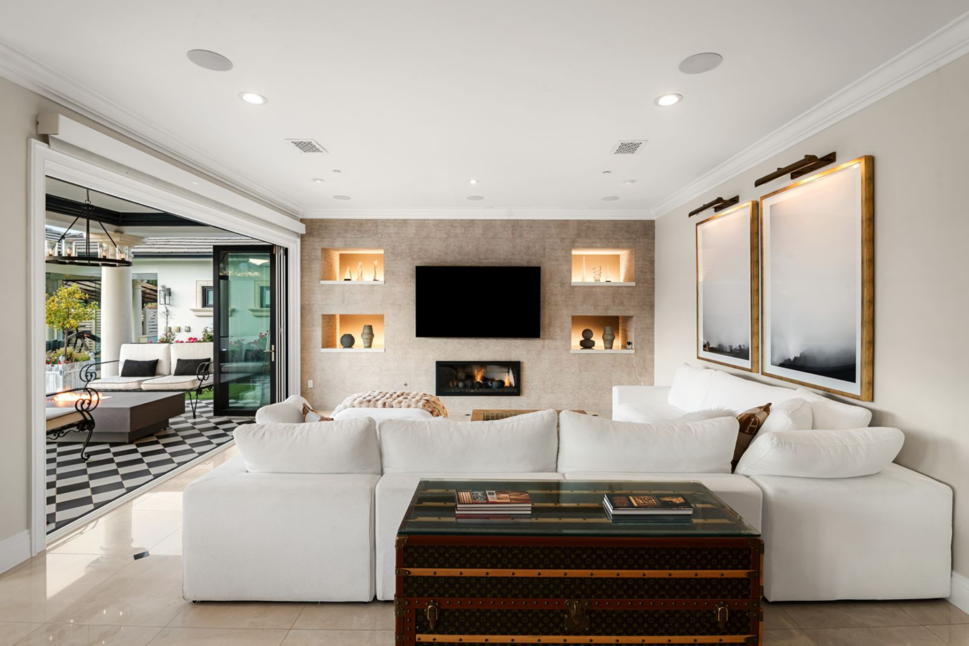 The seating is arranged around a central fireplace wall, where a built-in surround with recessed niches frames the television, keeping everything aligned and centered within the space.