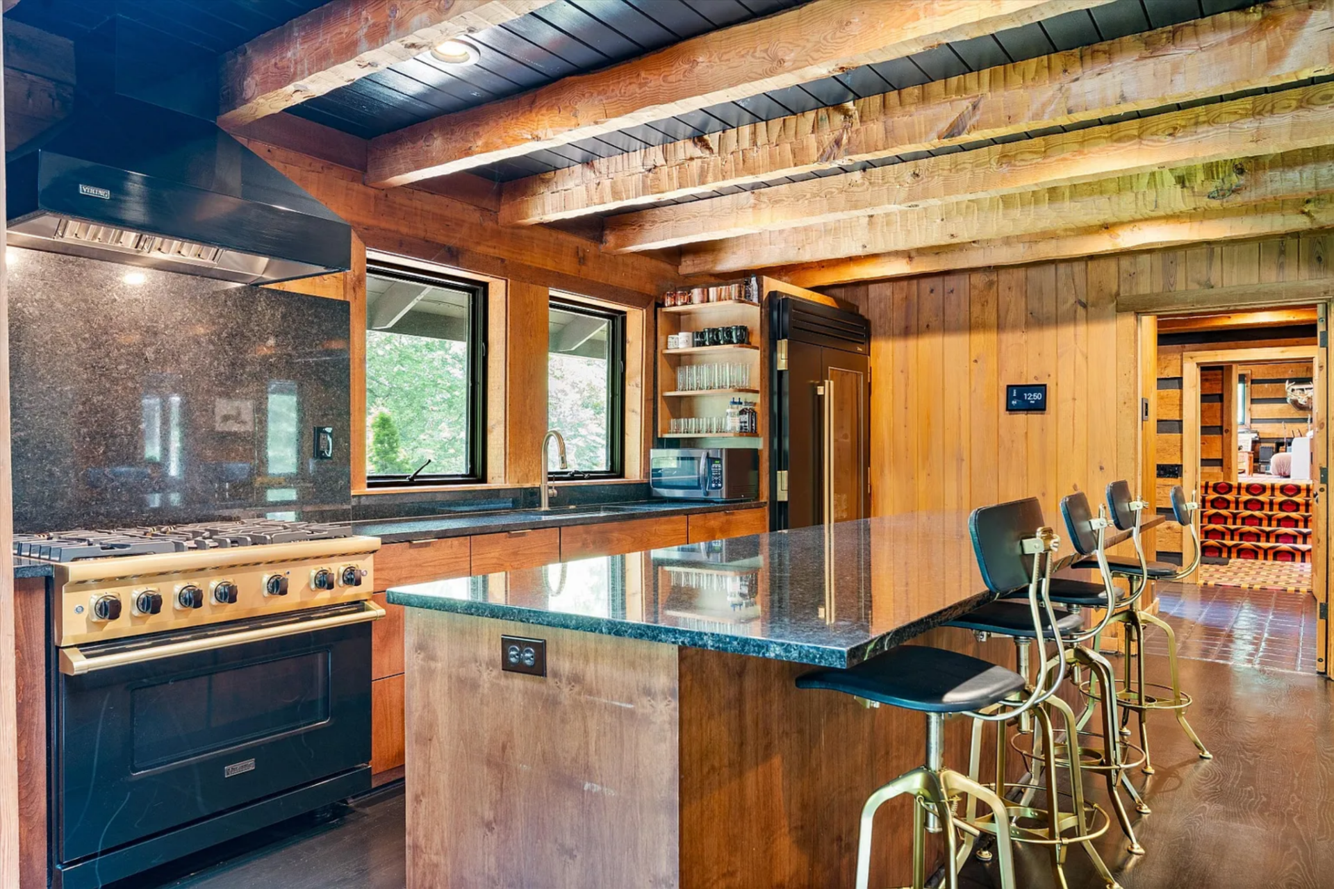Just beyond the dining area, the kitchen is centered around a large rectangular island fitted with a dark stone counter and a row of industrial-style bar stools along one side.