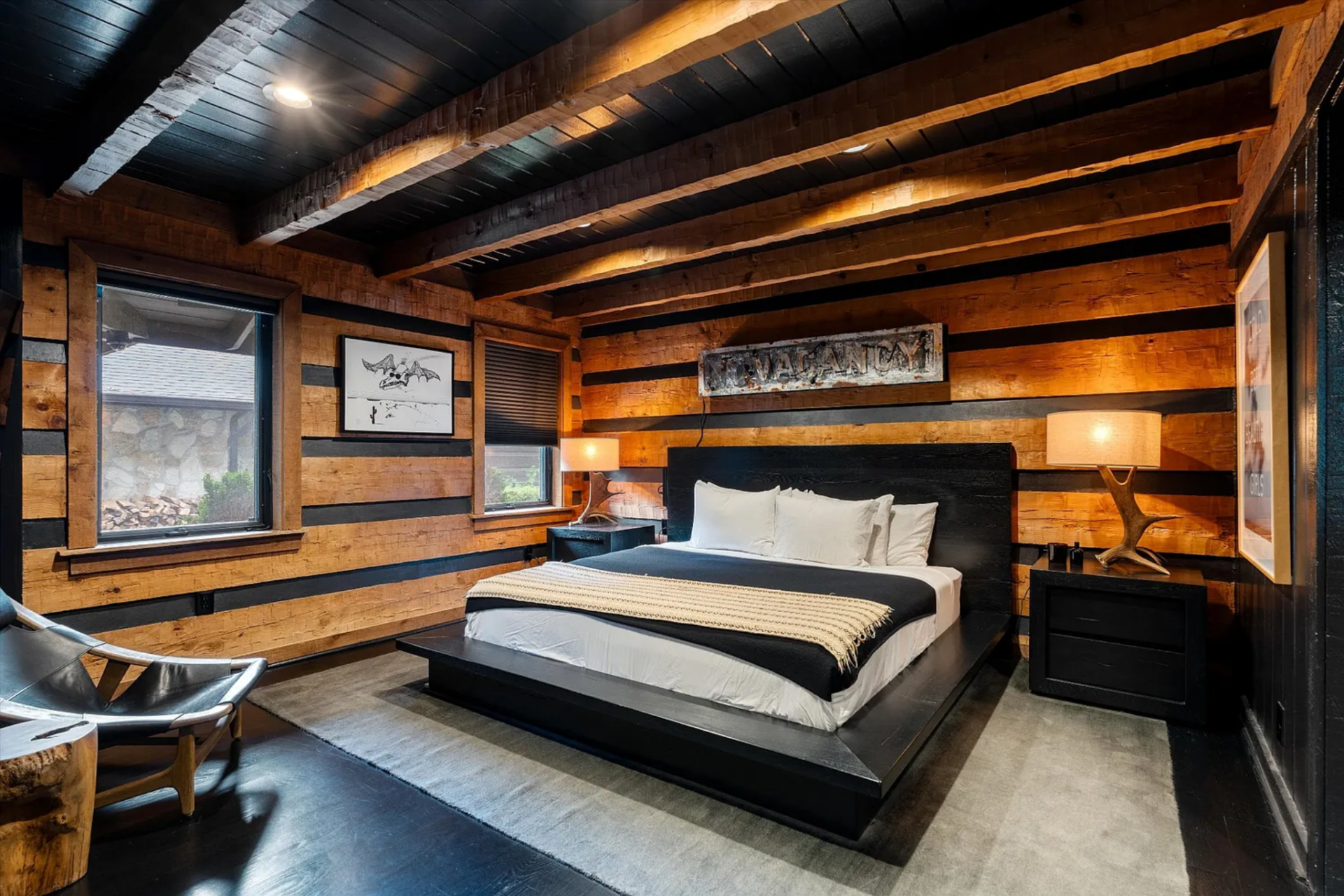Down the hall, the primary suite features a low platform bed centered against the wall framed by a pair of nightstands, table lamps, with a lounge chair in the corner.