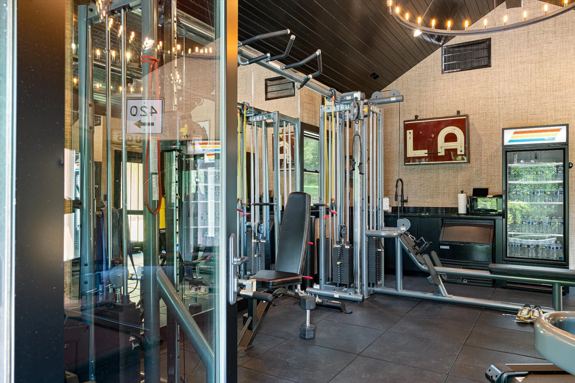 Inside, the barn opens into a fully outfitted gym, with strength-training equipment arranged across rubber flooring. 