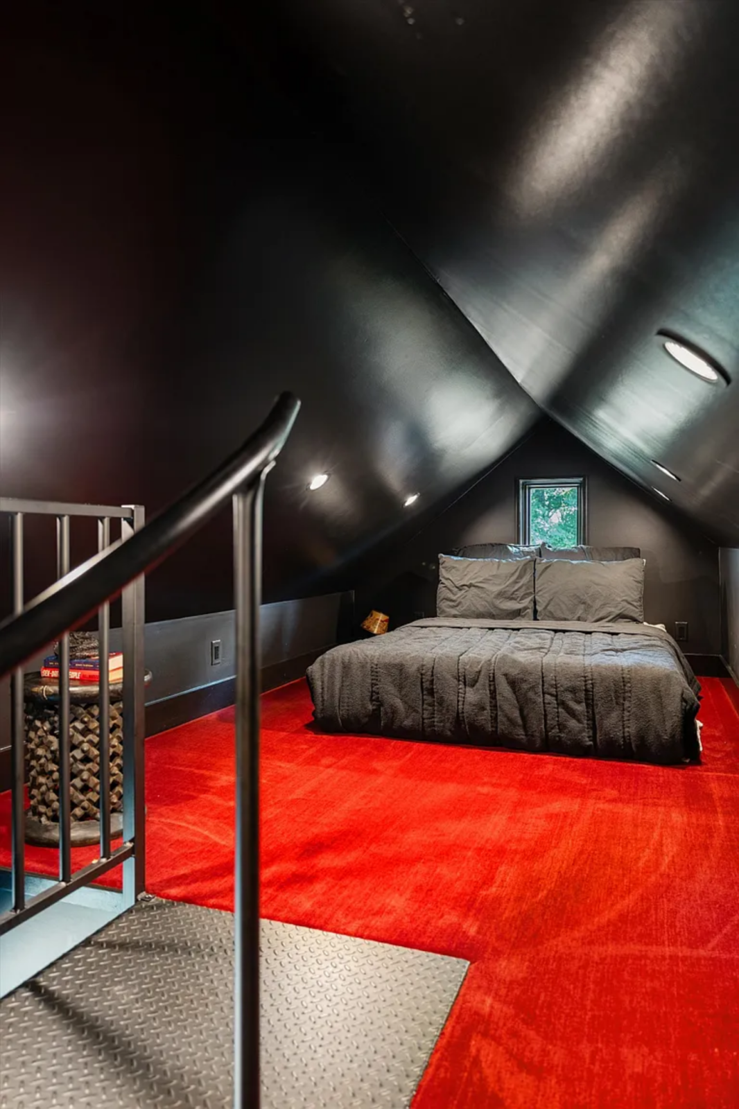 The second sleeping area is tucked beneath the pitched roofline, where the ceiling angles downward to create a loft-like atmosphere. 