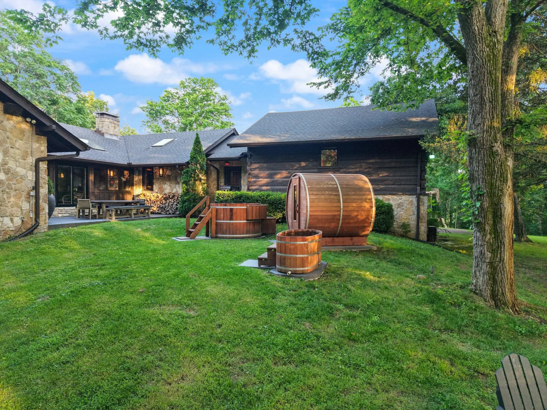 Just off the main house, a dedicated wellness setup brings together a barrel sauna, cold plunge, and a raised wooden soaking tub.
