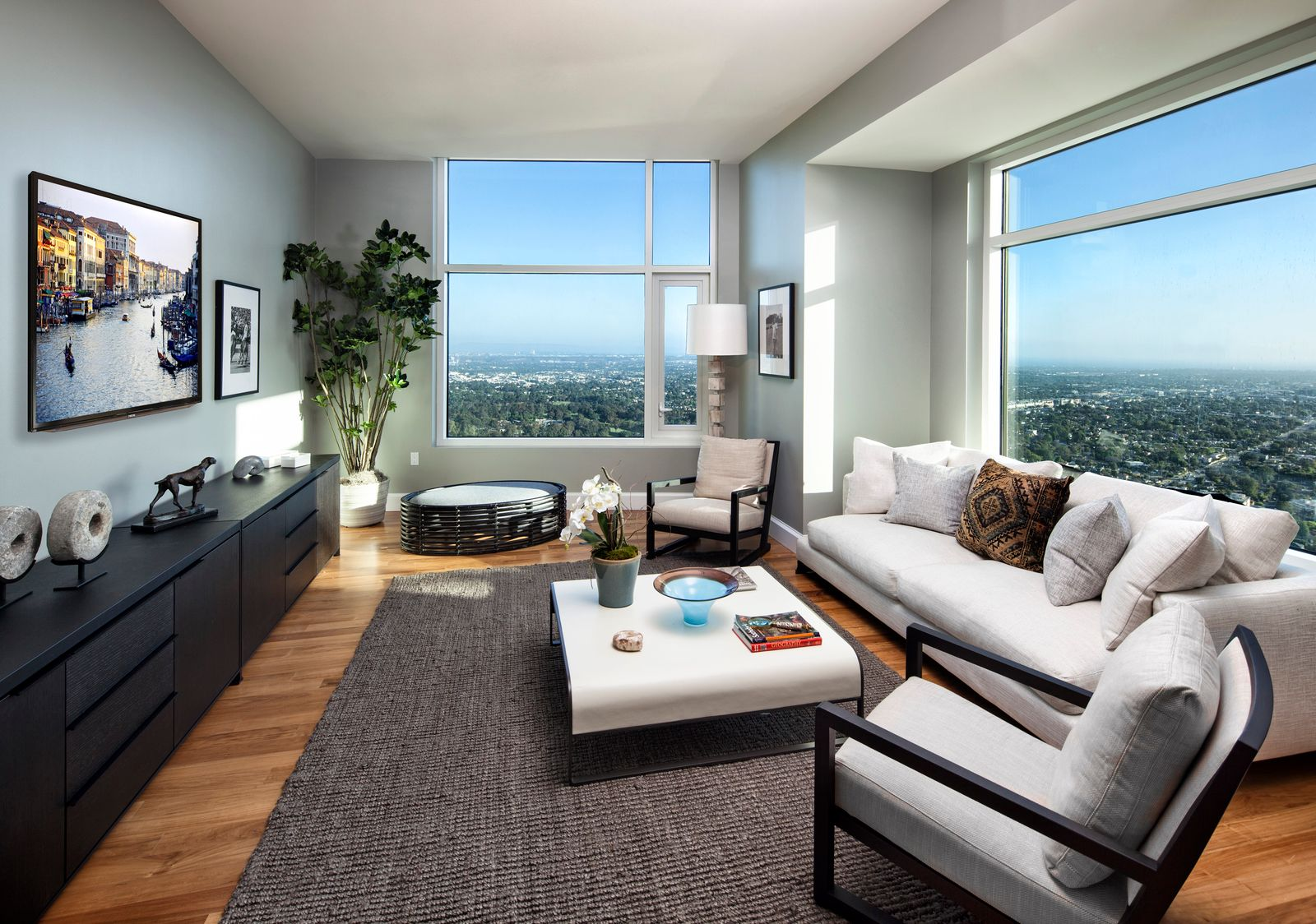 The layout is simple and relaxed, with a low-profile sofa, a pair of chairs, and a central coffee table arranged over a textured rug. 