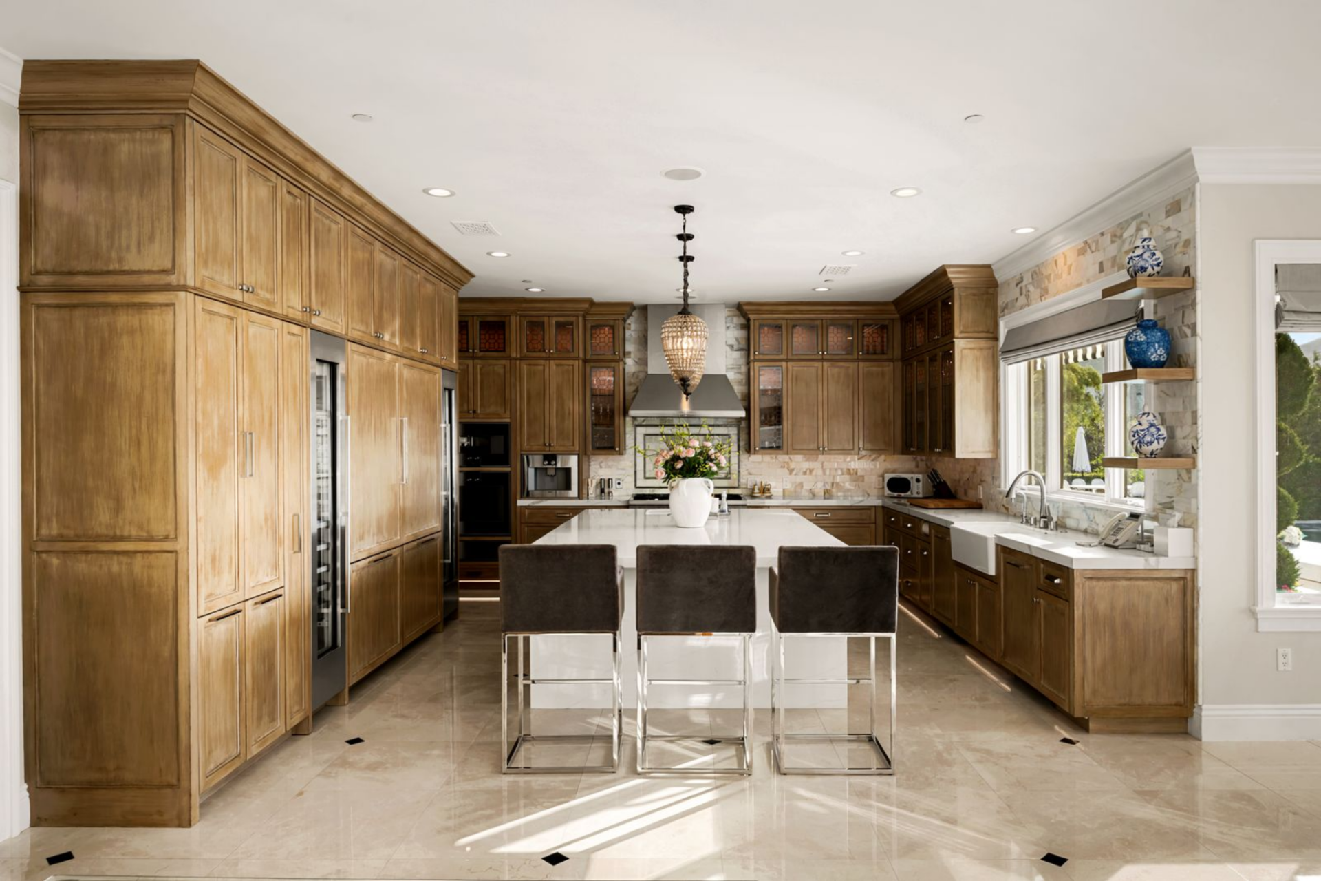 The kitchen sits directly behind the living room, laid out around a large island with a pair of pendant fixtures hanging over it in the center of the space. 