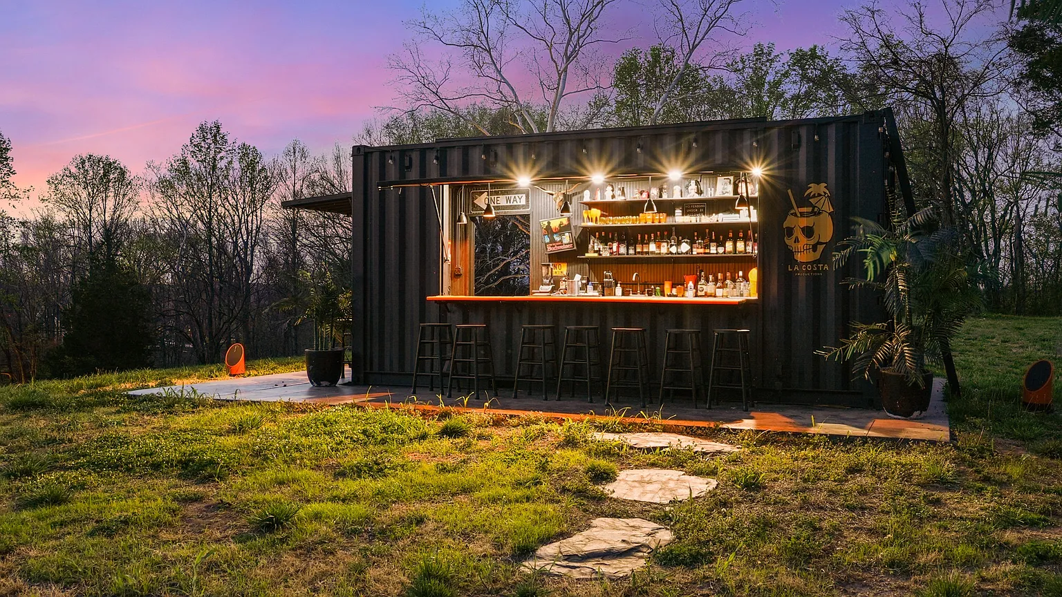 A few steps from the pool, a custom container bar adds an entertaining element to the pool area, its dark exterior contrasting with the landscape while housing a full-service bar that supports larger gatherings and outdoor hosting.