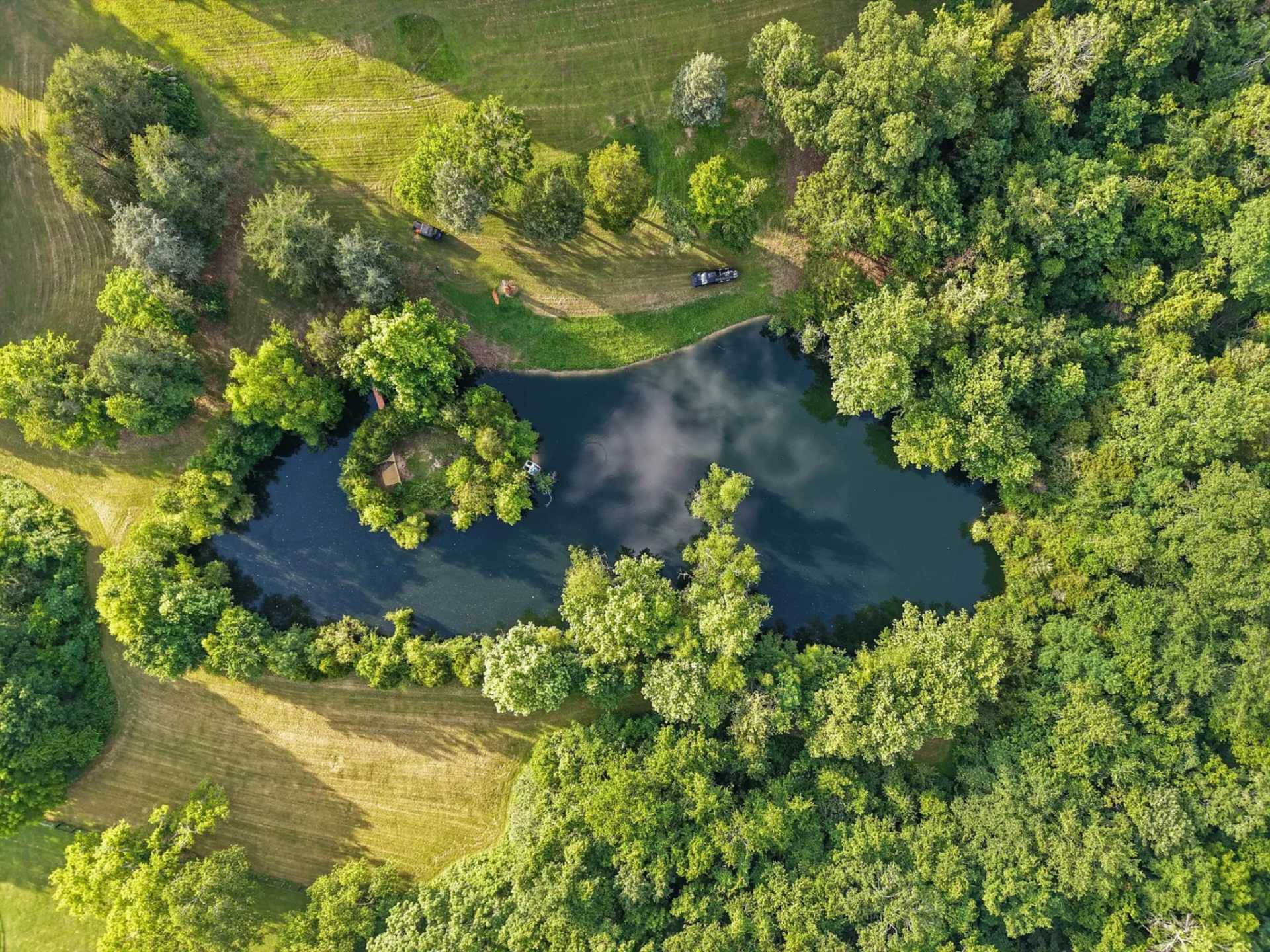 From above, the second pond is edged by trees and open grass, reinforcing the property’s mix of maintained land and more organic, wooded terrain.