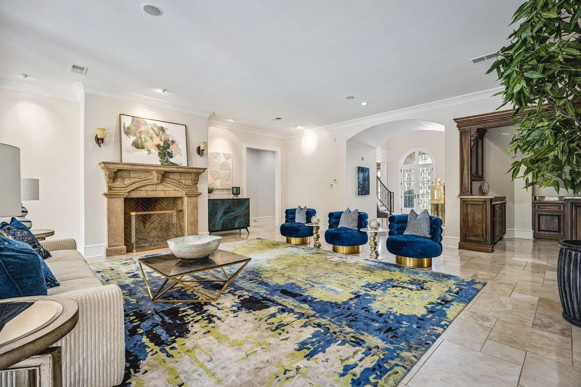 At the center, a low coffee table sits between a neutral sofa and a row of deep blue lounge chairs with rounded backs and gold bases, arranged to face inward.