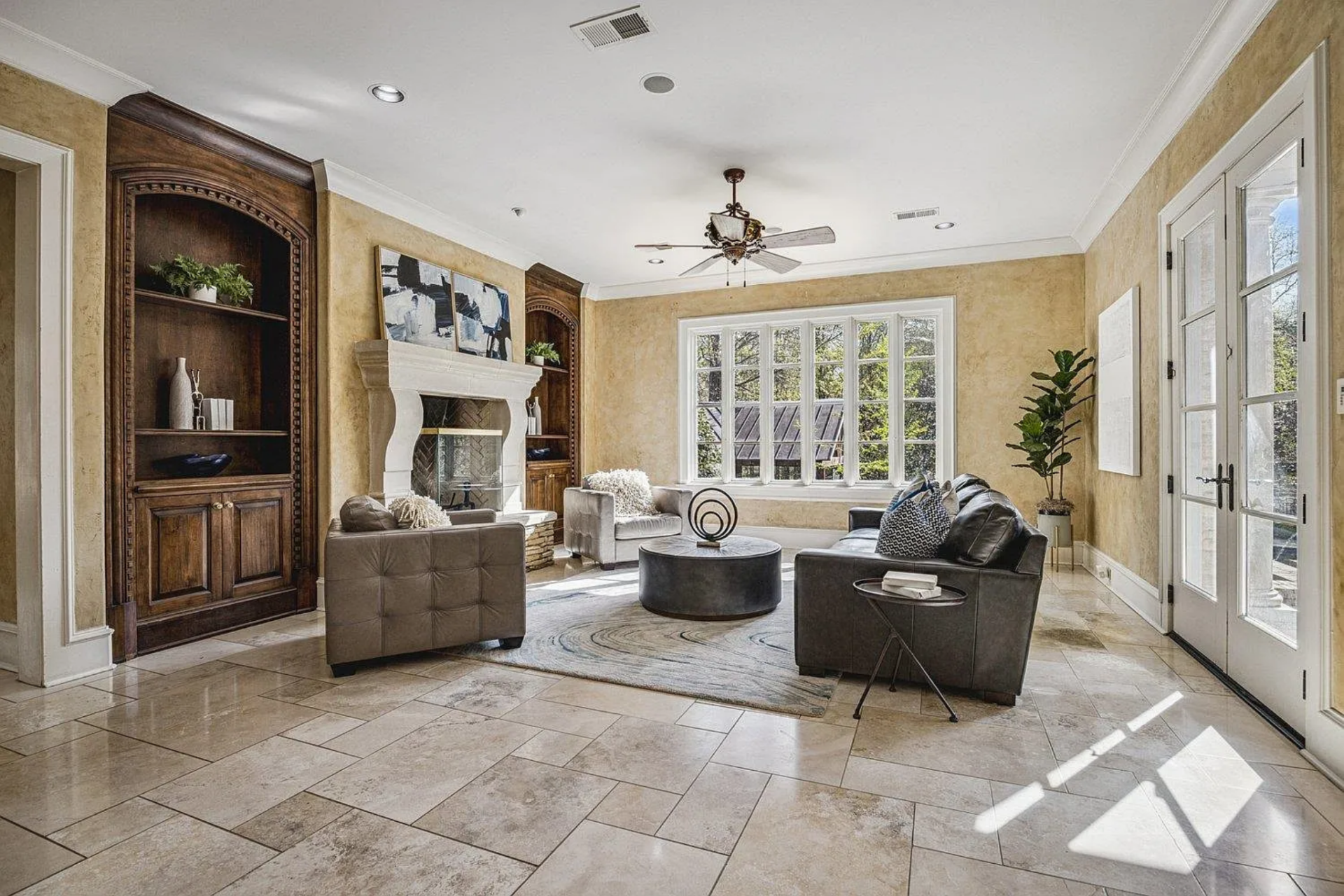 The seating area is arranged around a circular coffee table, with a mix of leather and upholstered chairs positioned to face the fireplace and one another.