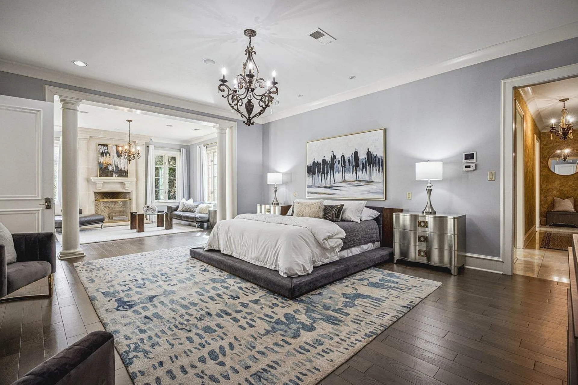 The bedroom opens with a wide footprint, centered around a low platform bed set over a large patterned rug.