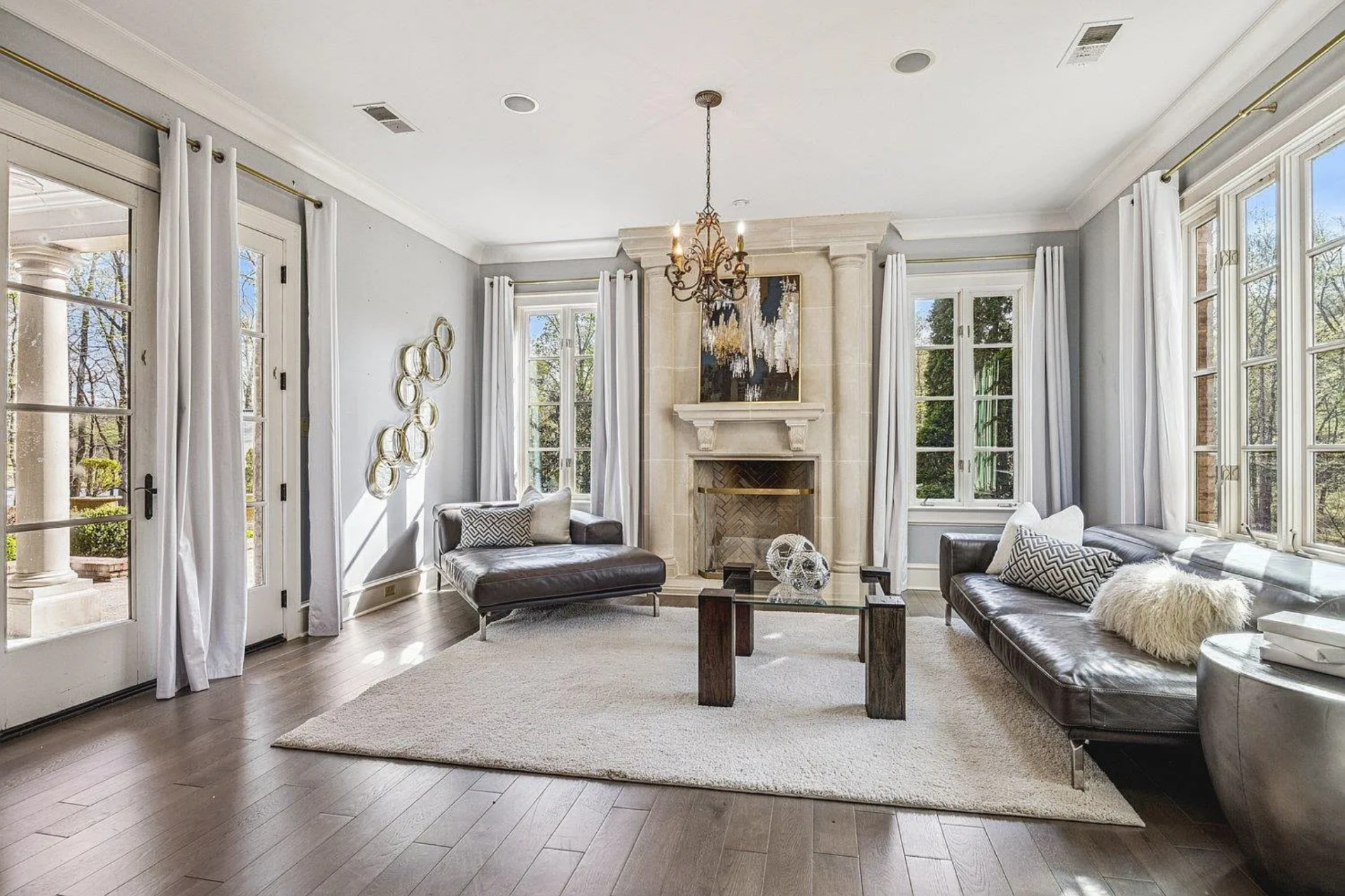 A pair of sofas and a glass coffee table face inward, surrounded by tall windows and French doors.
