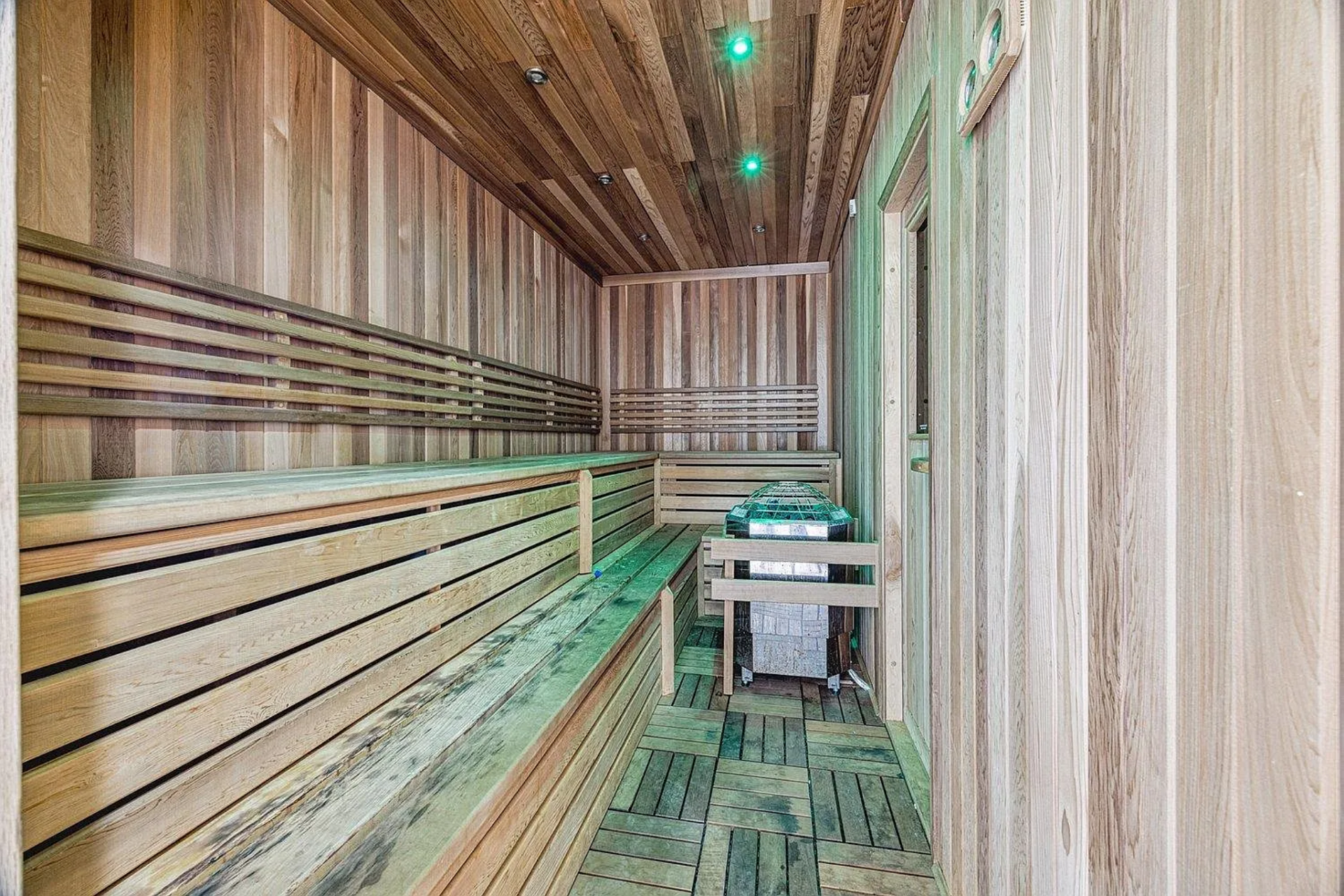 The sauna introduces a dedicated wellness element to the mansion, constructed with warm wood paneling, tiered bench seating, and integrated lighting.