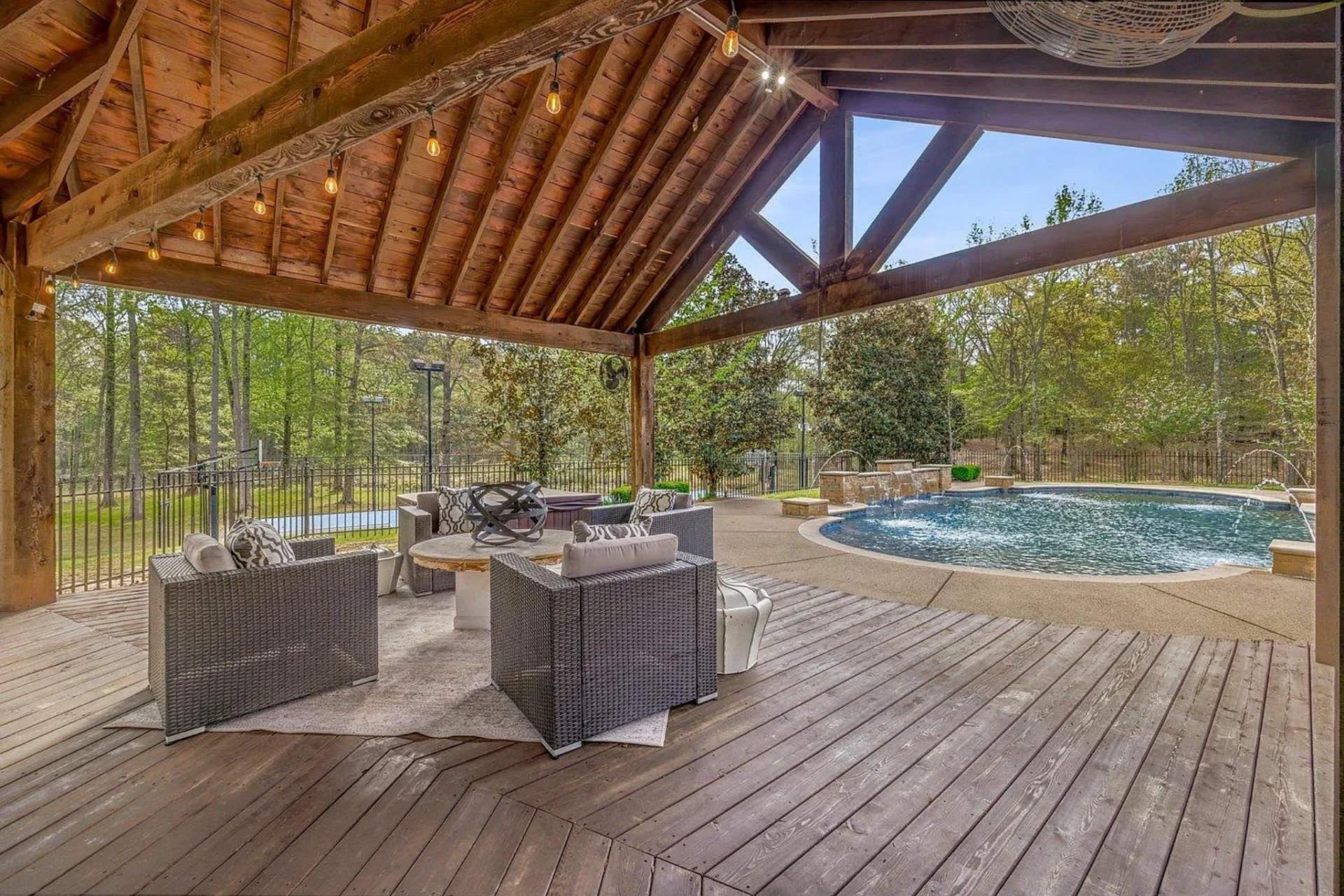 A covered gazebo extends the usability of the space, featuring a vaulted wood ceiling, exposed beams, and integrated lighting.