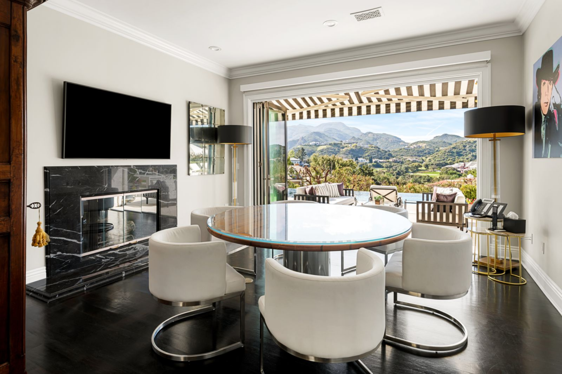 Just around the corner, the formal dining room is set up as a more intimate extension of the main living areas, with a round glass-topped table centered in the space and surrounded by sculptural upholstered chairs.