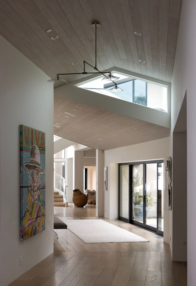 A wall lined with mirrors draws you in, reflecting light and adding depth, while a short set of steps leads the way up to the main living areas through a short hallway lined with wood plank flooring.