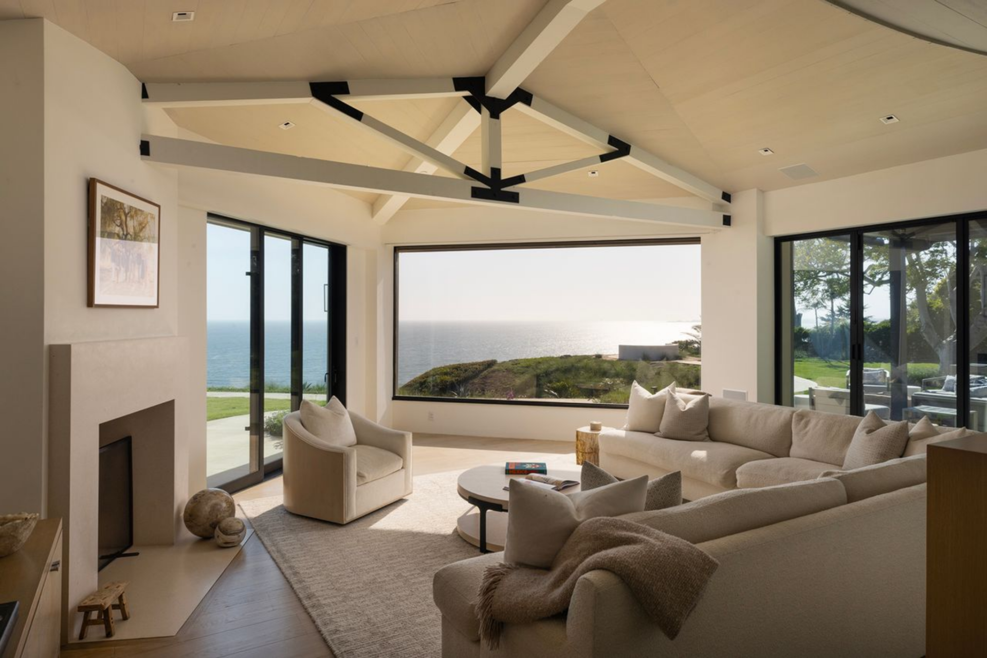 The family room continues the home’s clean, coastal palette with a curved sectional and matching lounge chair gathered around a simple round coffee table.