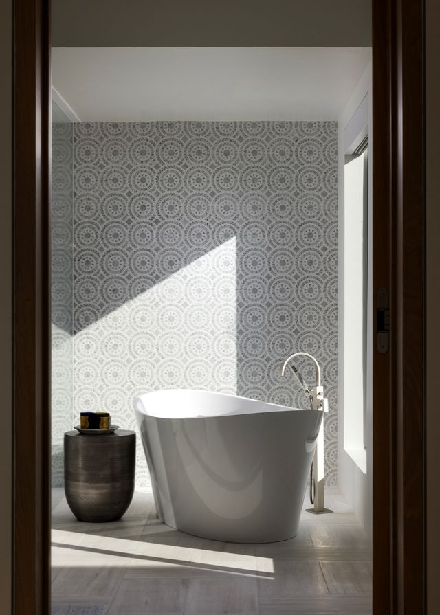 Opposite the vanity, a glass-enclosed shower and freestanding soaking tub are positioned to take advantage of the view, with a large picture window framing the landscape outside. 