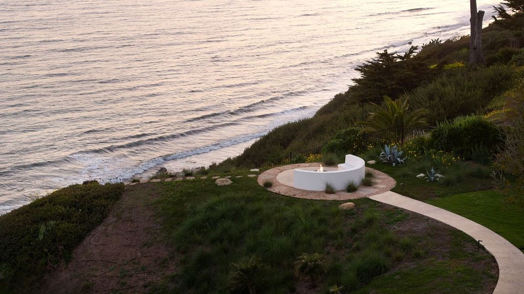 At the bluff’s edge, a curved firepit lounge is carved into a circular pad overlooking the ocean. 