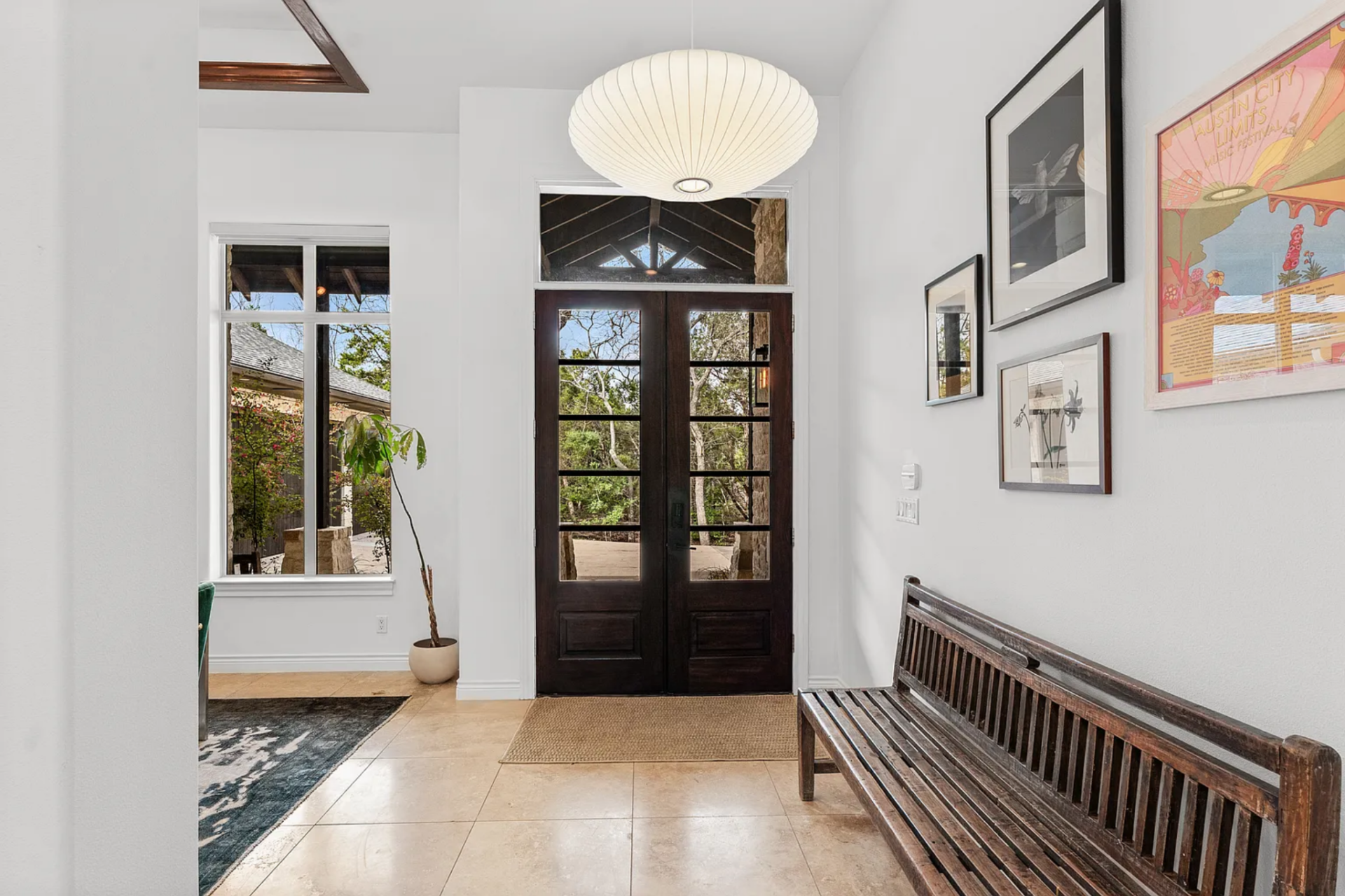 Along one side of the entry, a long wood bench sits beneath a row of framed artwork, giving the foyer a clean, grounded edge without adding visual clutter. 