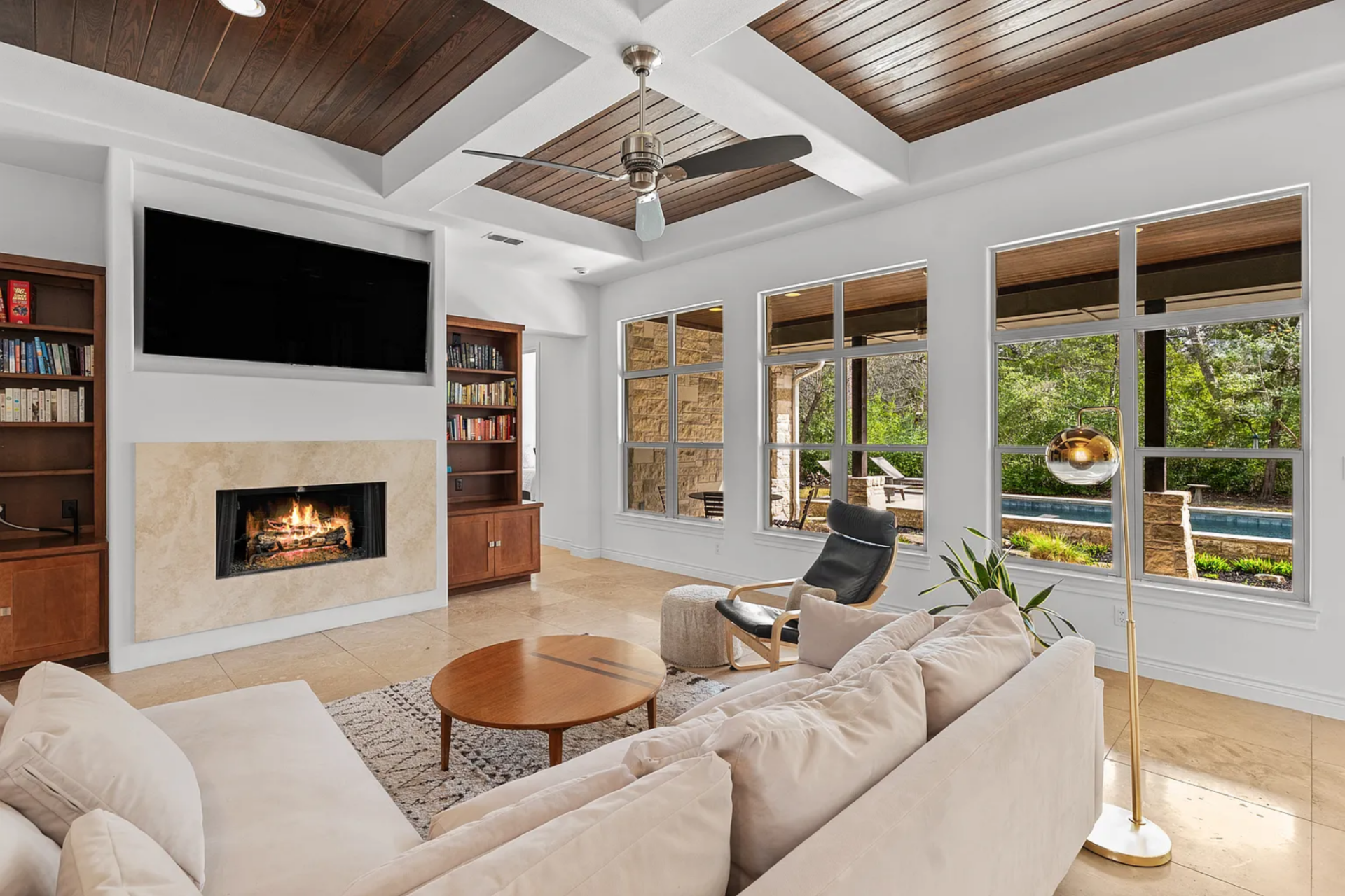 Along the far wall, a fireplace is set beneath a mounted television and framed by built-in bookshelves. 