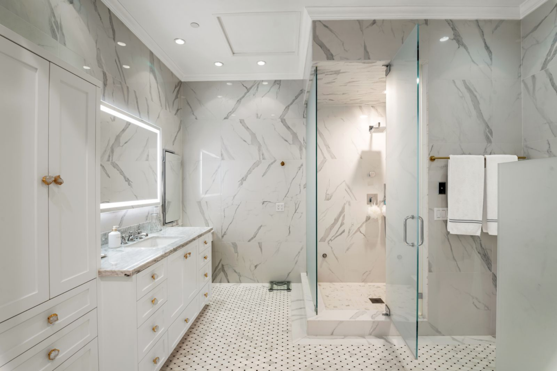 The second bathroom shifts to a brighter palette, with full marble surfaces wrapping the walls and floors. 