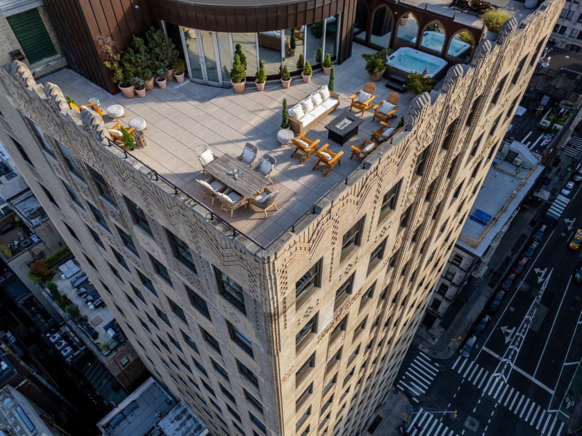 Stepping outside, the penthouse opens onto a rooftop terrace that wraps the top of the building with broad paved seating areas, decorative brick parapets, and views of the Hudson River, the Manhattan skyline, and the surrounding Tribeca rooftops.