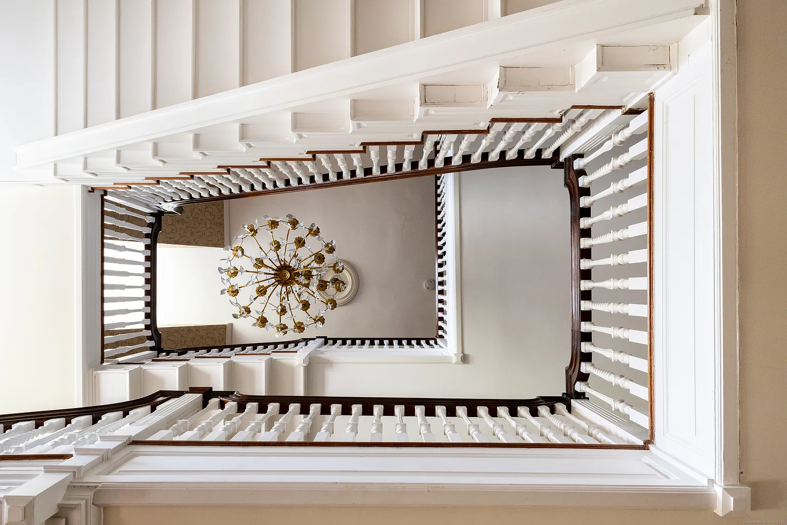 Straight ahead, the staircase rises from the center of the hall and up through all three levels of the home with a white balustrade and paneled stair surround that keeps the detailing crisp. 