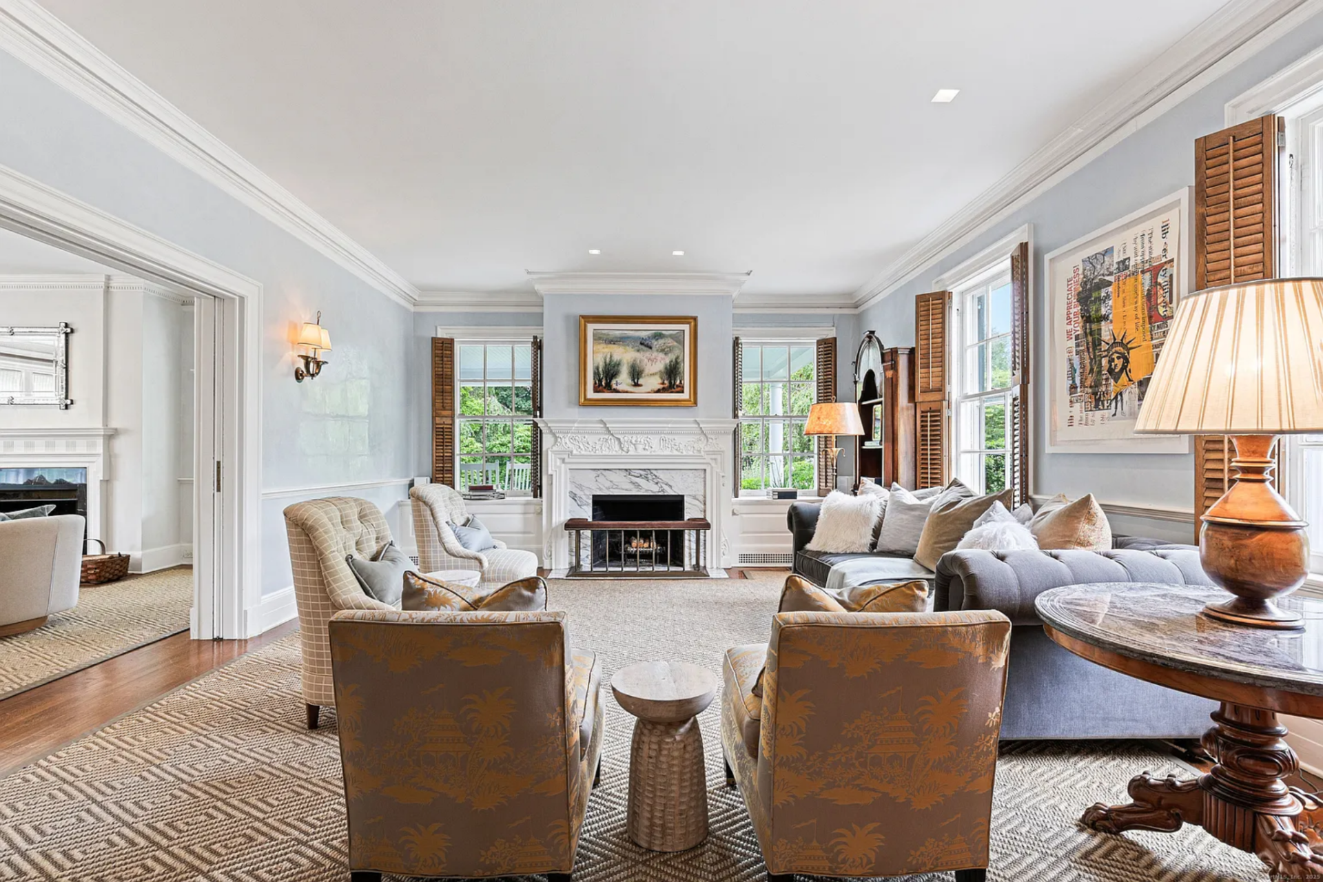 From there, the seating is spread across the room, with a deep tufted sofa along one side, a pair of high-back armchairs facing inward, and two patterned accent chairs closer to the foreground.