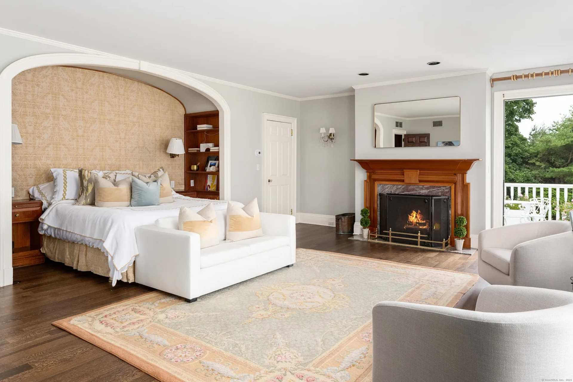 In the bedroom, a wide arched alcove frames the bed with matching wood nightstands and shelving tucked into either side. 