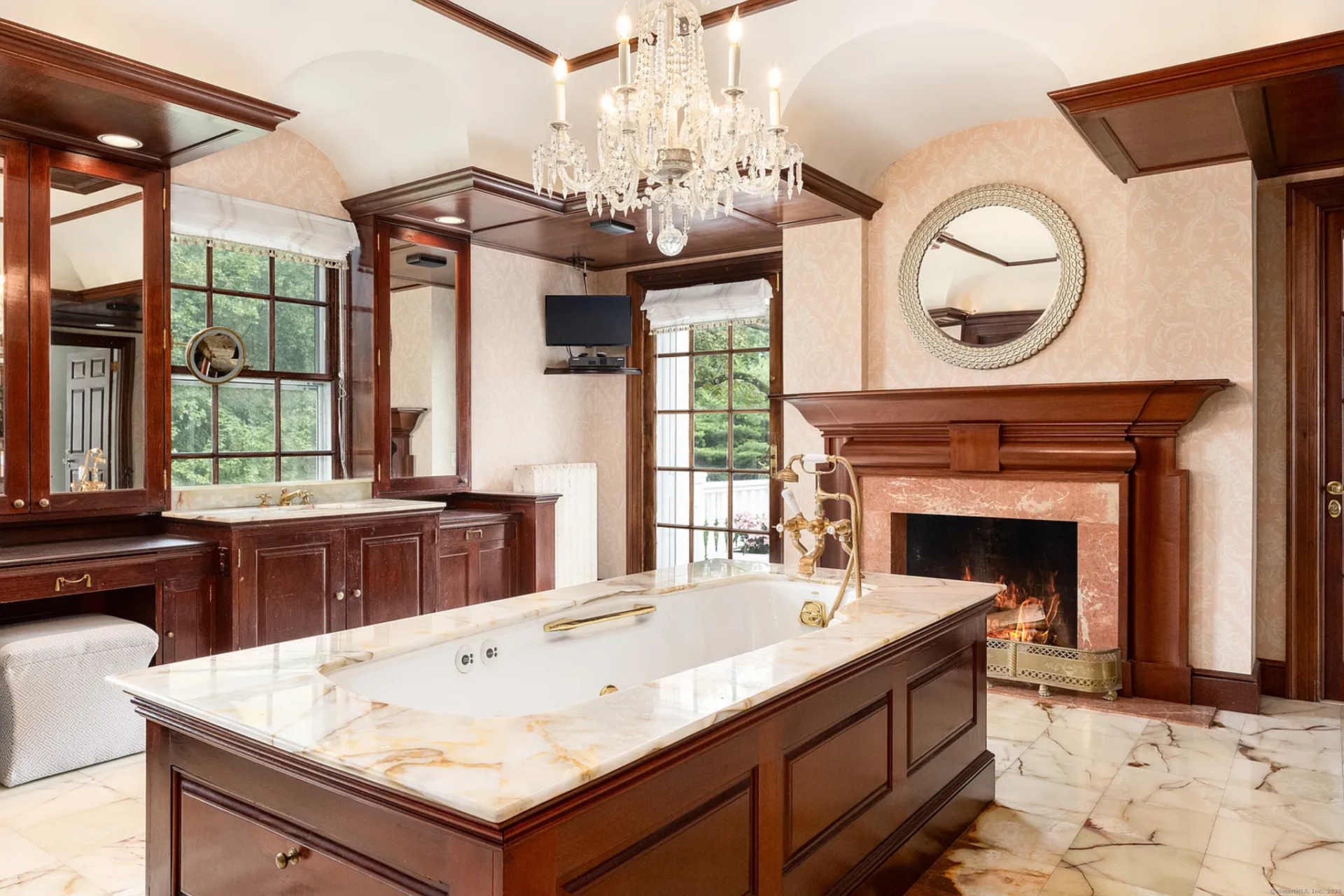 On one end of the rub sits a curved glass-block shower and a fireplace sits at the other while the side of the room is lined with dual vanities.