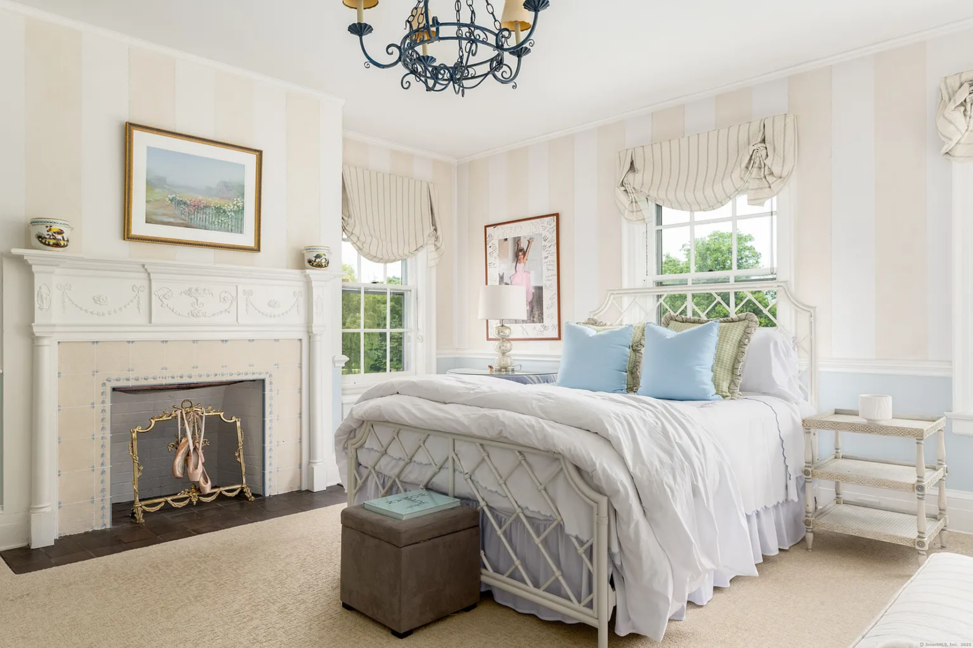 Soft striped walls, pale blue lower paneling, and gathered Roman shades give the room a lighter, more traditional look, while the chandelier and framed artwork add to the dressed-up feel.