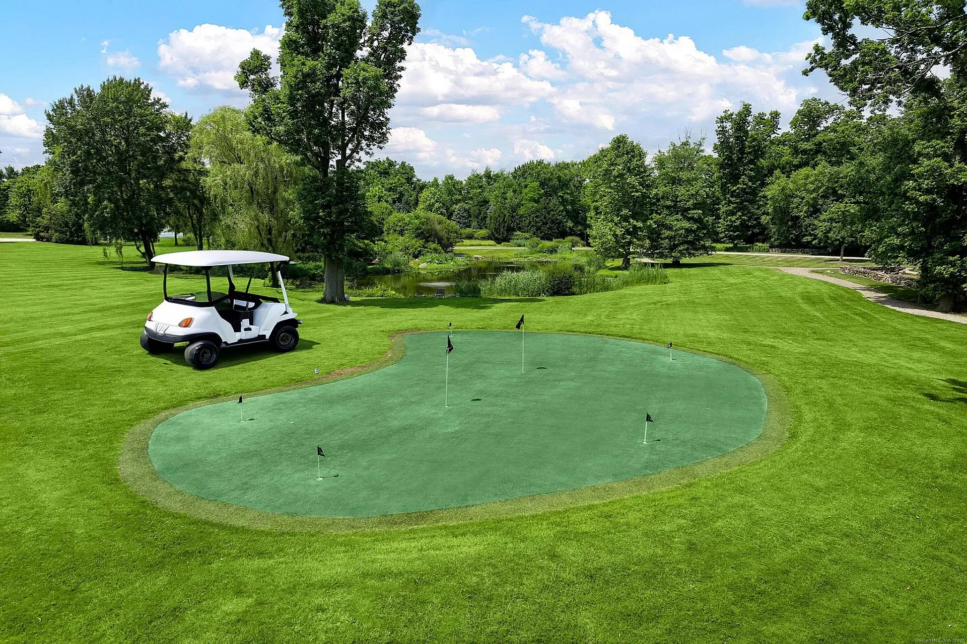 There is also a golf putting green set out on the lawn, positioned with long views back toward the pond and mature trees. 