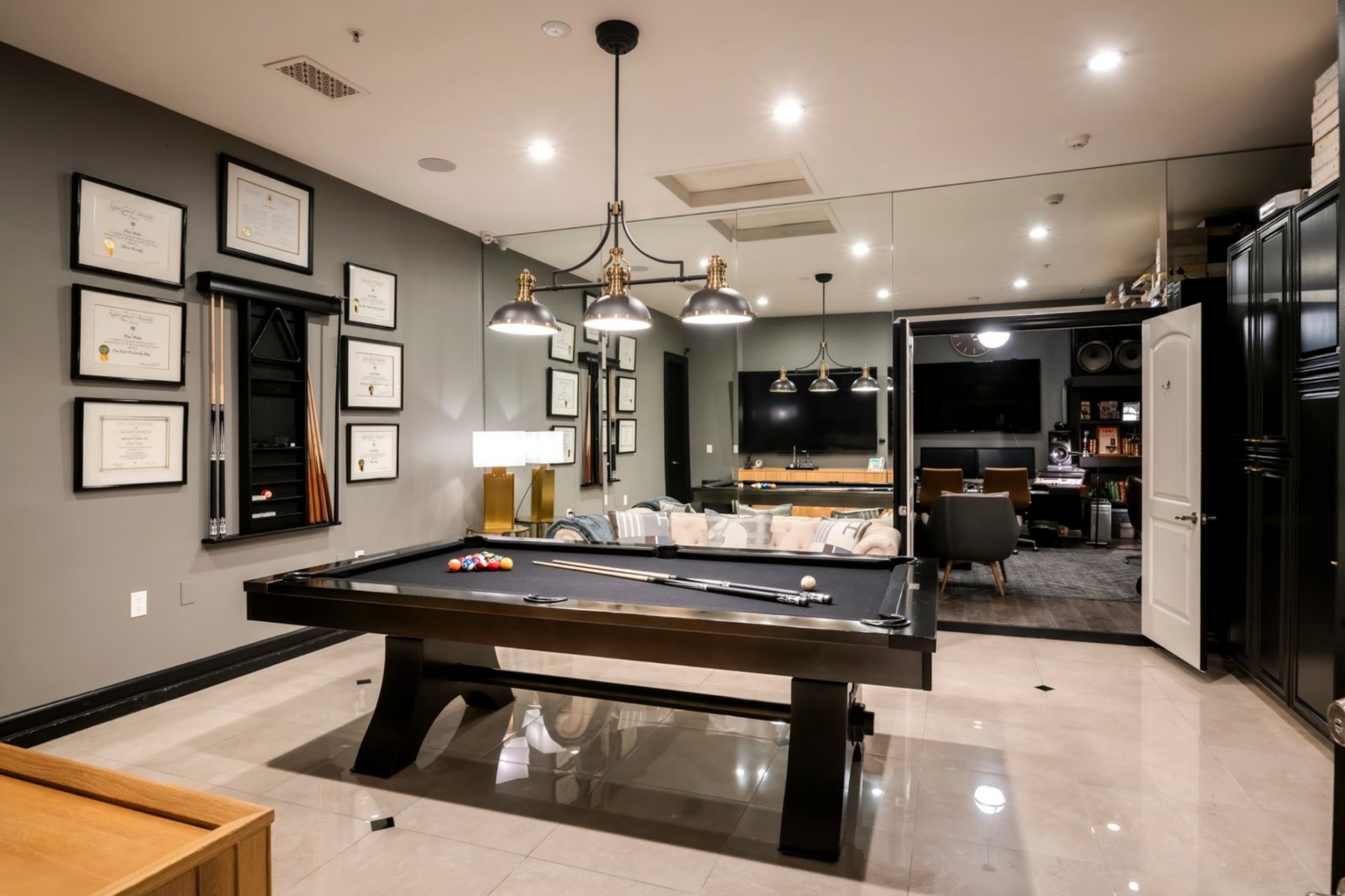 The billiards room is centered around a full-size pool table, positioned beneath a trio of pendant lights that define the playing area. 
