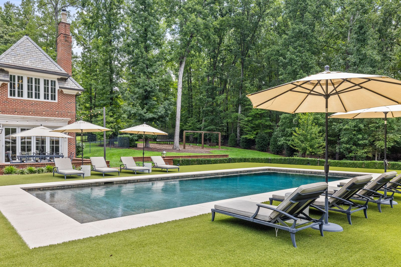 Stepping out from the back of the home, the pool sits on a slightly elevated plane, framed by clean lines of turf. 