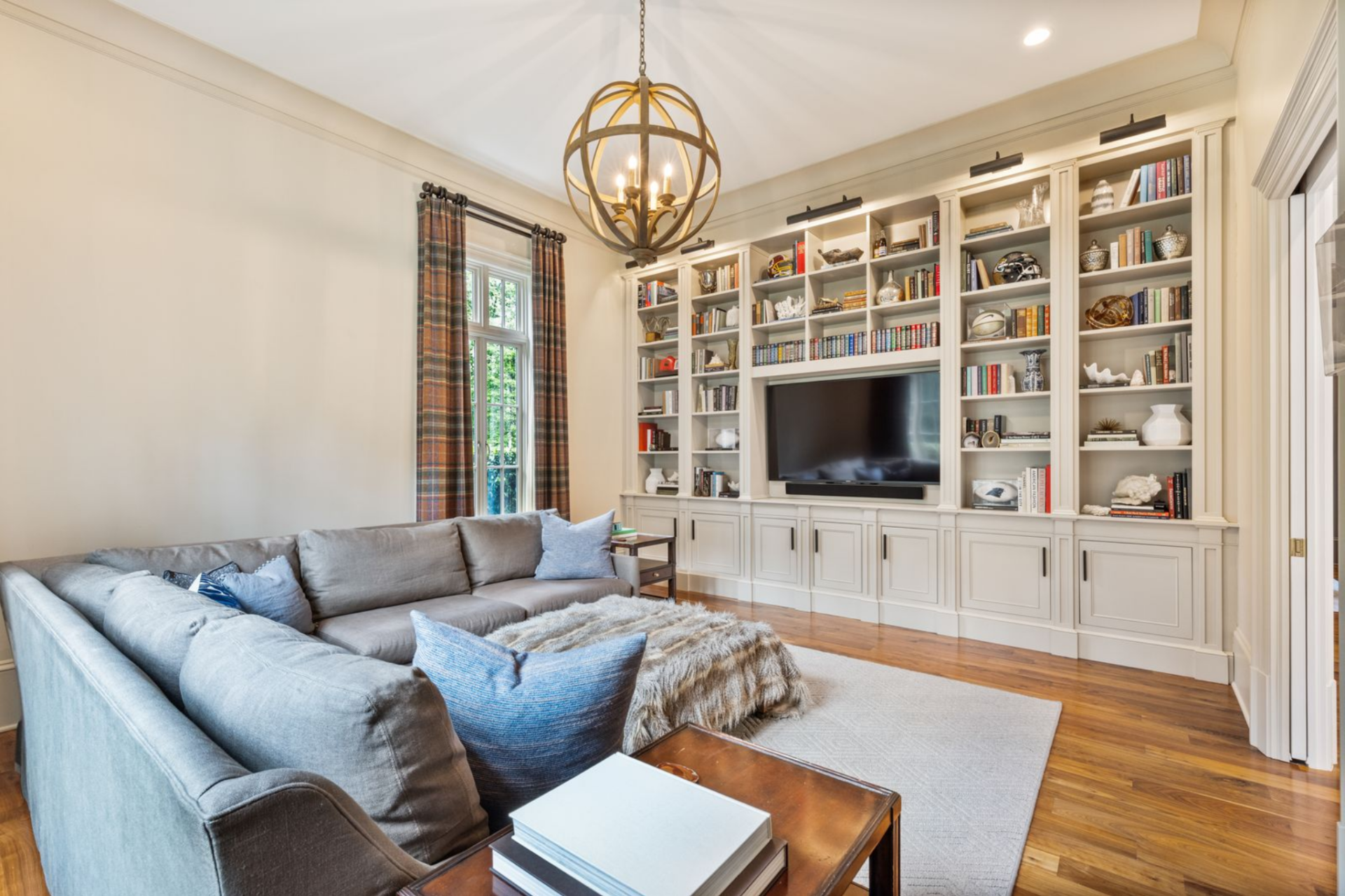 Just past the entrance, the media den is centered around a full wall of built-in cabinetry and shelving, with the television set into the middle.